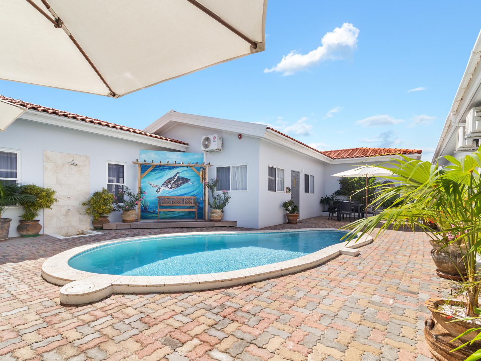 Refreshing Shared Pool Area of the Apartment in Noord Aruba - Dive into a refreshing poolside escape - Unwind with a dip in our chic and stylish pool area - Potted plants for a refreshing and lively ambiance