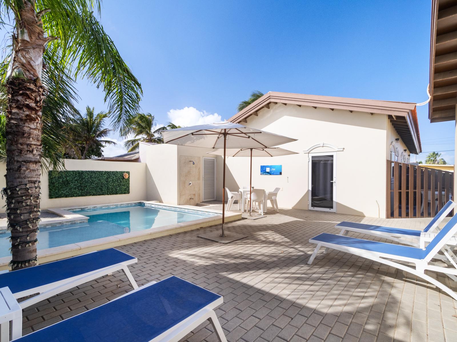 Luxury pool area of the apartment in Noord Aruba - Lush and refreshing environment - Cozy beach chairs available - Beautifully sunbathed space makes the soul peaceful - Experience the comfort at the best