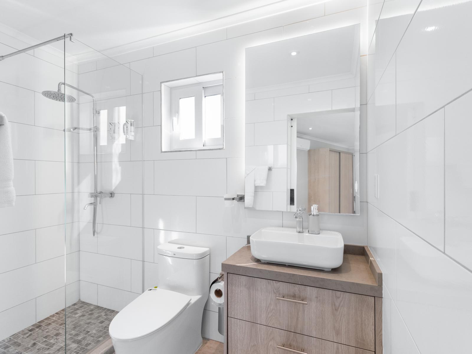 Lavish Bathroom of the Apartment in Noord Aruba - Chic design featuring a sleek vanity and upscale lighting - Spacious layout offering a sense of luxury and comfort - Polished Vanity with Large Mirror - Glass-enclosed shower for a modern touch