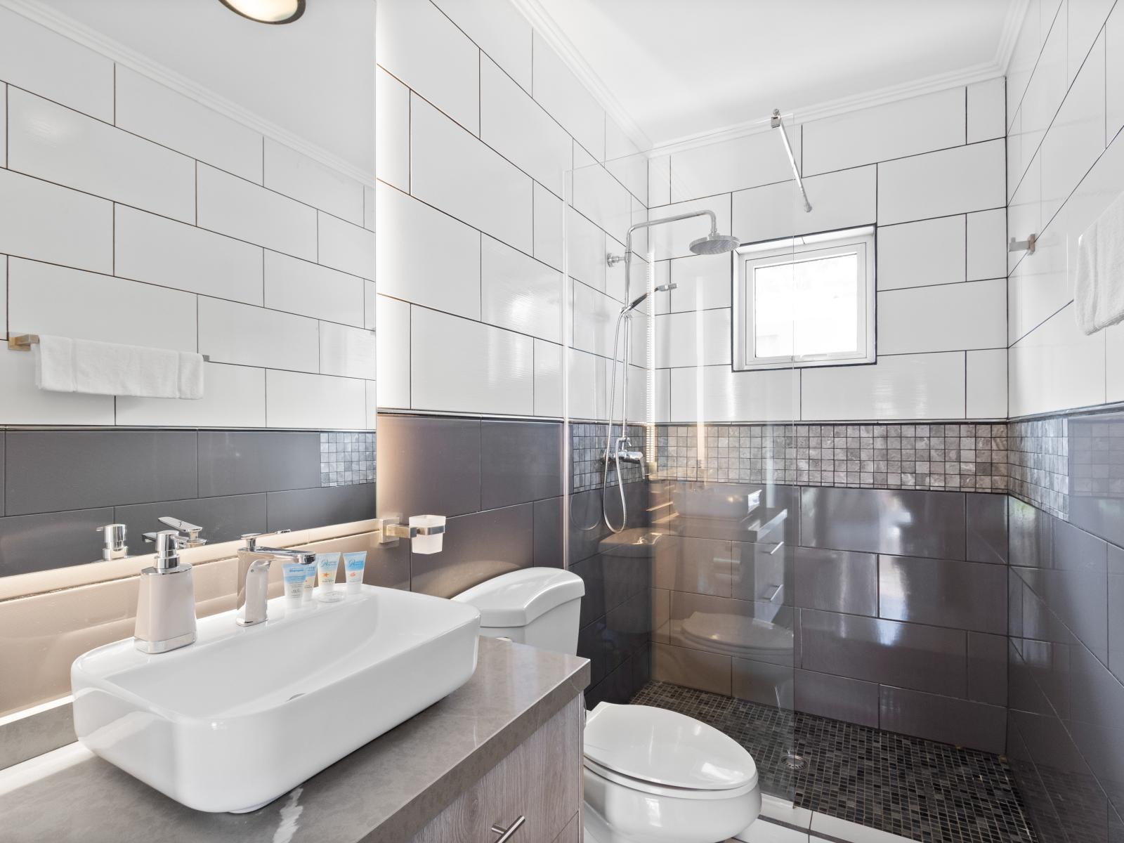 - Exclusive Bathroom of the apartment in Noord, Aruba - Beautiful Vanity with large size wall mirror - Sufficient storage space - Neat and clean toilet seat - Availability of all bathroom amenities - Stunning glass cabin shower area
