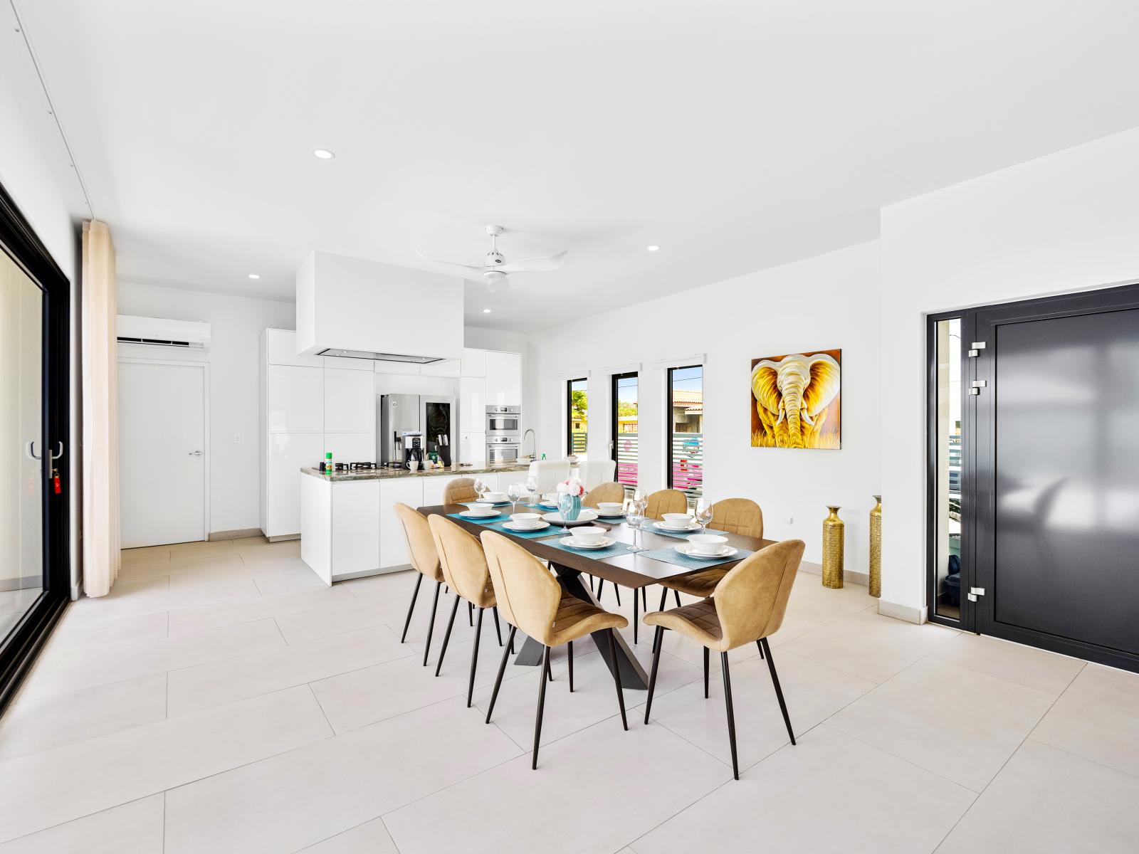 Thoughtfully organized dining area of the home in Noord, Aruba - Stunning 8 persons dinning table in front of the open kitchen - Beautifully decorated space with lovely wall paintings - Big and bright doors leading to the backyard