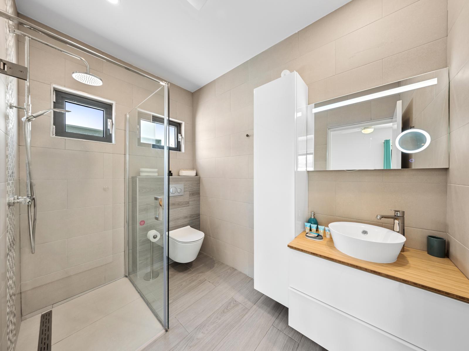 Indulge in our pristine bathroom of the home in Noord, Aruba - Unwind in your own private oasis, complete with a walk-in shower area and all bathroom amenities - Enjoy the convenience of plush towels, premium toiletries, and thoughtful touches