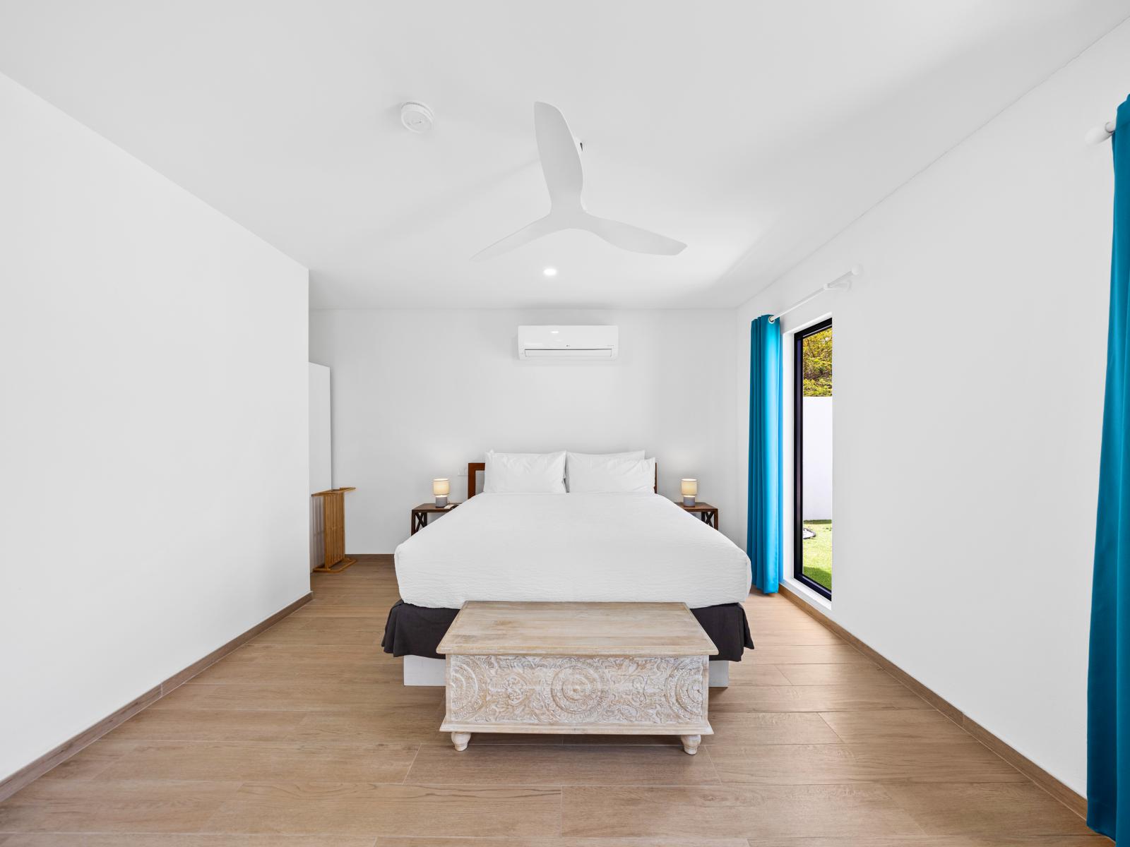 Drift into relaxation mode in this bedroom of the home in Noord, Aruba - Immerse yourself in the elegance of this white themed bedroom with wooden furnished floor - A cozy double bed retreat promising a relaxing sleep