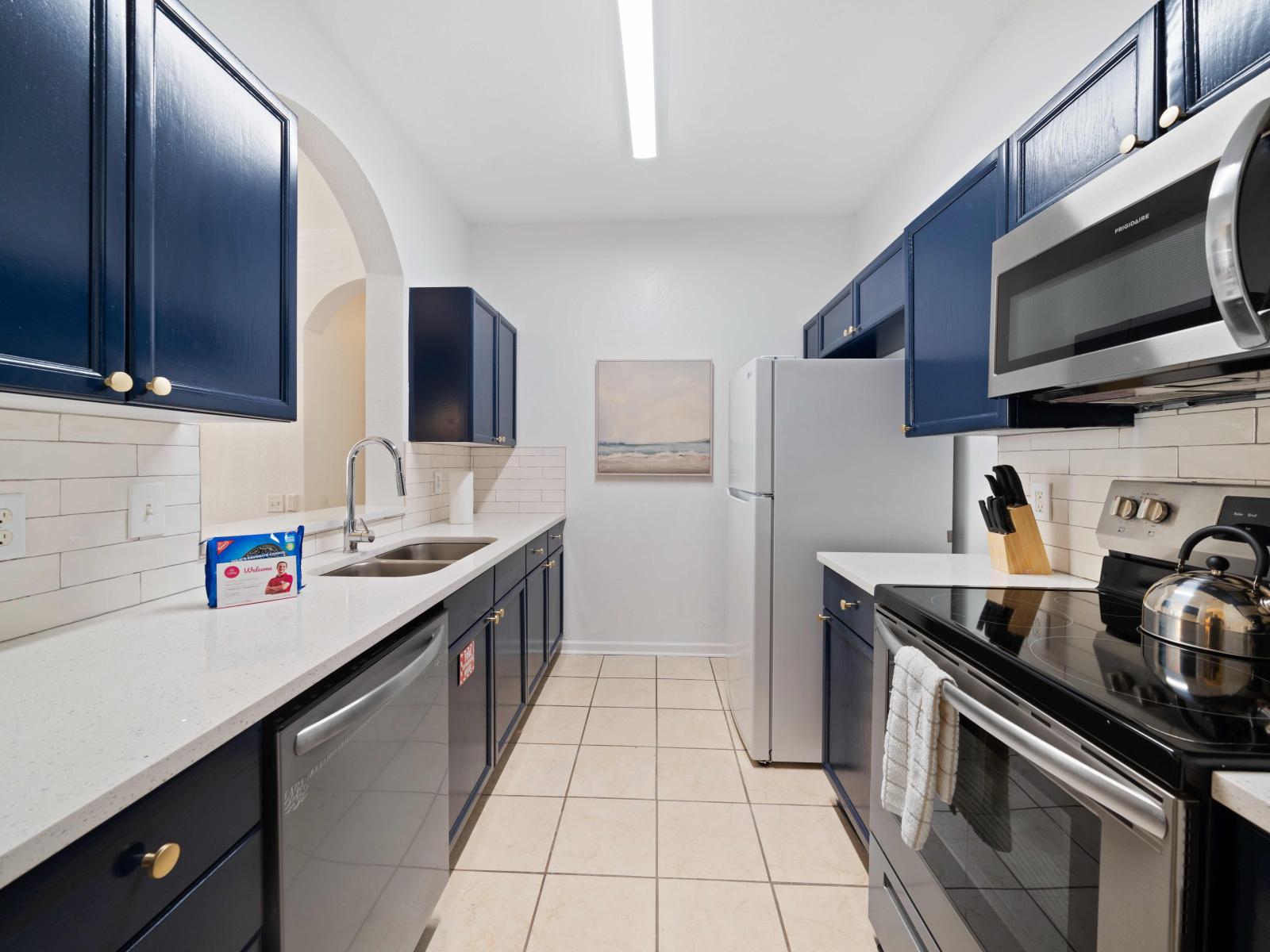 Stylish kitchen of the condo in Kissimmee, Florida - Fully stocked kitchen boasting plenty of room for culinary adventures - Kitchen with stainless steel appliances - Thoughtfully curated kitchen lighting, balancing functionality and ambiance