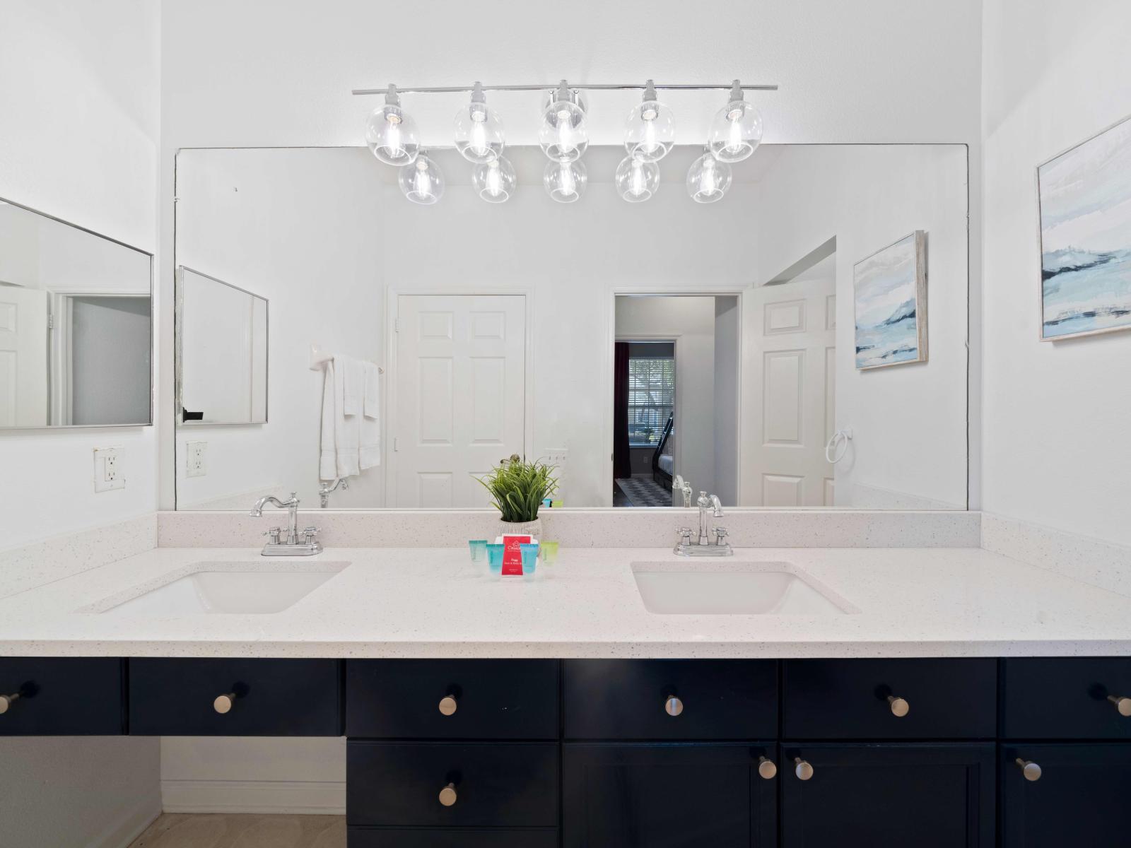 Elevated bathroom of the condo in Kissimmee, Florida - Beautiful vanity accompanied by a generously-sized wall mirror and dual sinks - Gentle illumination showcasing the beauty of the tile craftsmanship