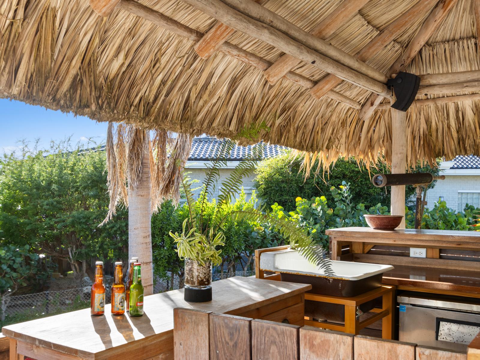 The tiki bar is surrounded by a lush green garden