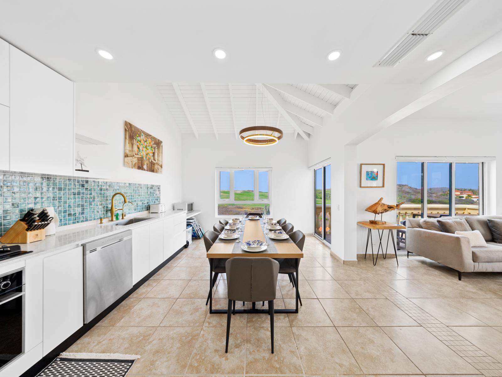 Modern kitchen and dining area of the condo in Noord Aruba - Kitchen has a beautiful blue backsplash - Well-planned layout maximizing comfort and functionality - Chic dining area featuring a stylish table and contemporary seating