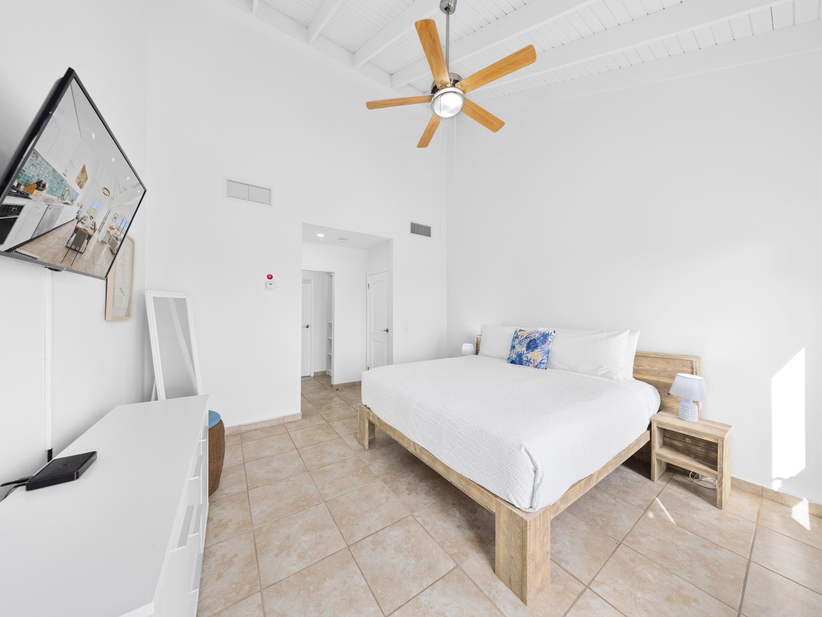 Alluring bedroom of the condo in Noord Aruba - Features an attached bathroom for privacy and convenience - Cozy retreat with a plush bed, perfect for relaxation - Full length mirror and minimalistic decor for clean sleeping space