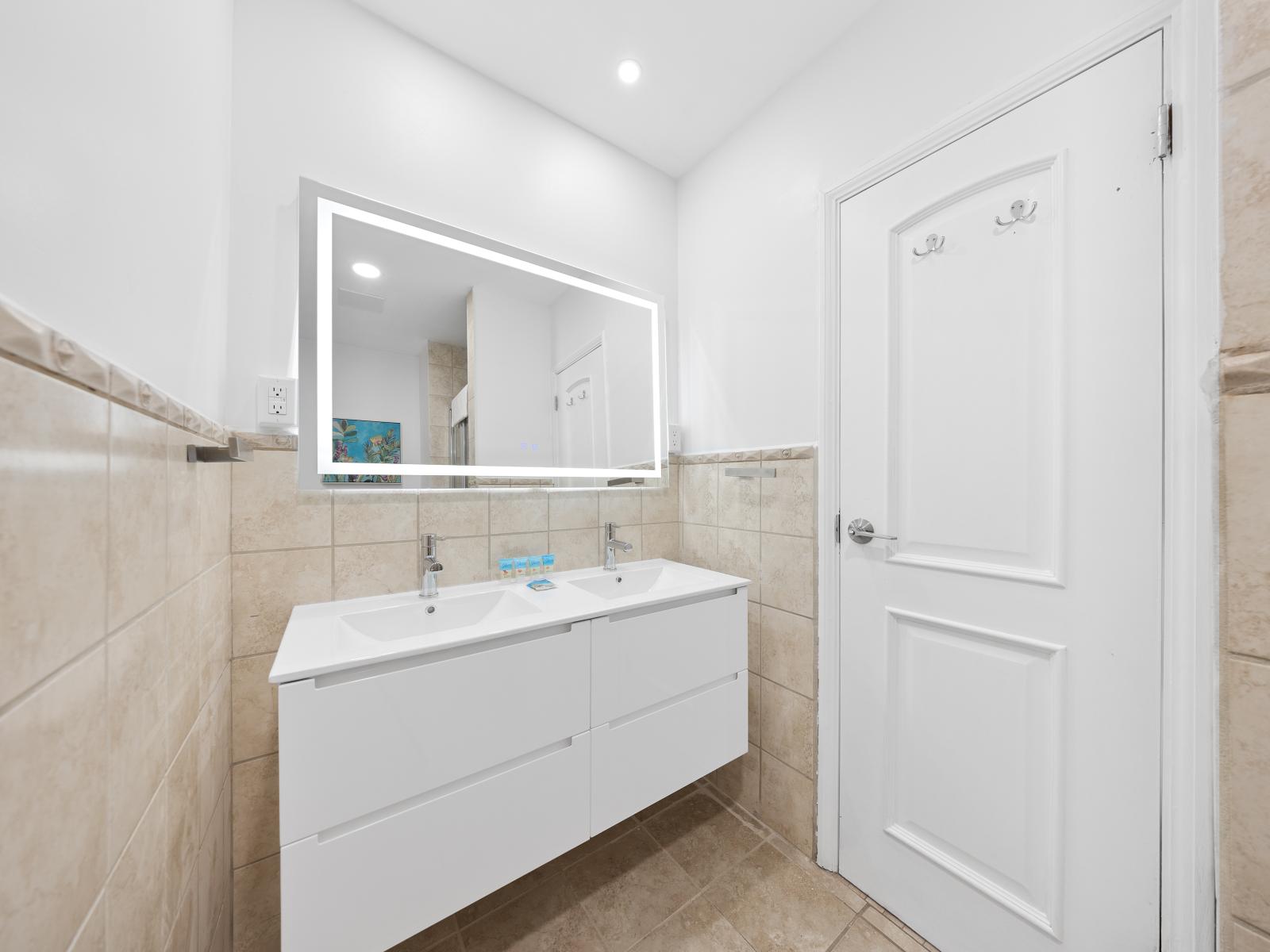 Tiled bathroom of the condo in Noord Aruba - Offers a walk in shower stall - Attention to detail, from the elegant tiles to the faucets - Chic dual vanity with large mirror and upscale lighting