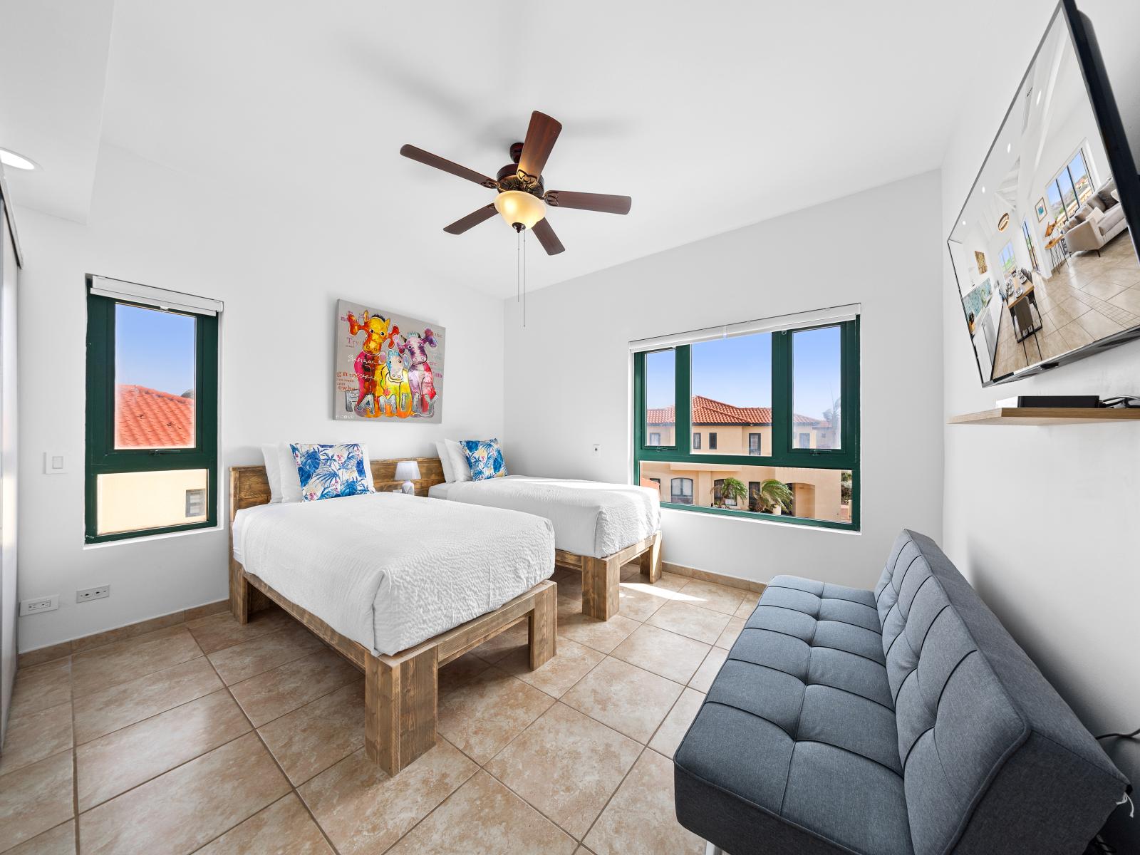 Cozy bedroom bed of the condo in Noord Aruba - Features 2 single beds and a sofa - Smart TV to stream your favorite shows and movies - Bright and airy bedroom with large windows for natural illumination