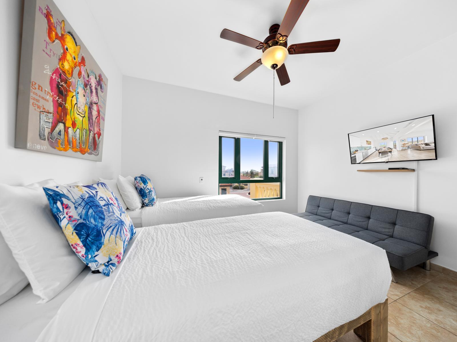 Comfy bedroom of the condo in Noord Aruba - Two single beds and a wall mounted flat screen smart TV - Minimalist decor, creating a clean and uncluttered sleeping space - Bedroom with a cozy ambiance, blending comfort and aesthetics