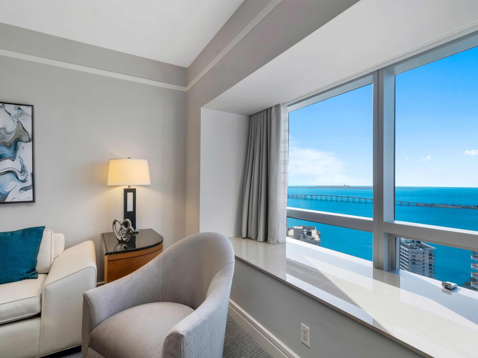 Seascape Sophistication: Dine and relax in sophistication in this living area with an unparalleled ocean view. Chic decor and the rhythmic sound of waves make this one-bedroom apartment a coastal haven.