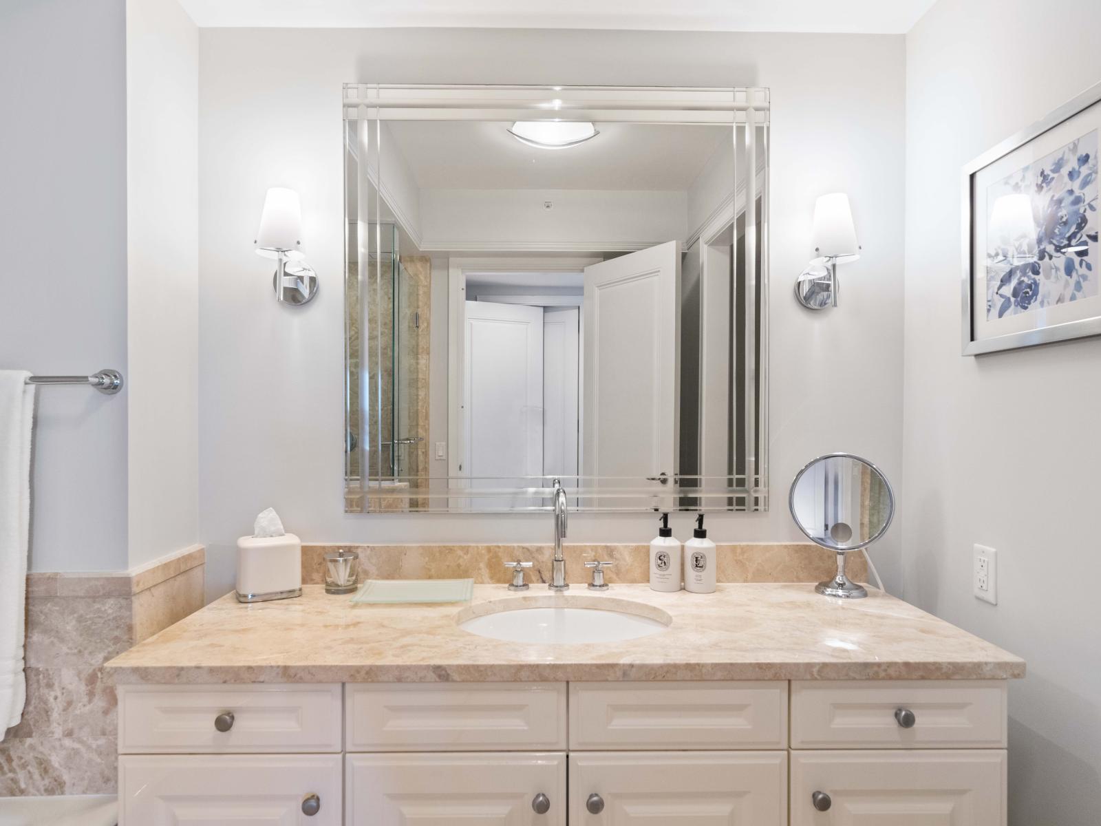 Swish Bathroom of the Condo in Miami Florida - Chic vanity with upscale lighting - Sophisticated color palette creating a serene ambiance - Contemporary fixtures for a touch of indulgencehtub and a walk-in shower