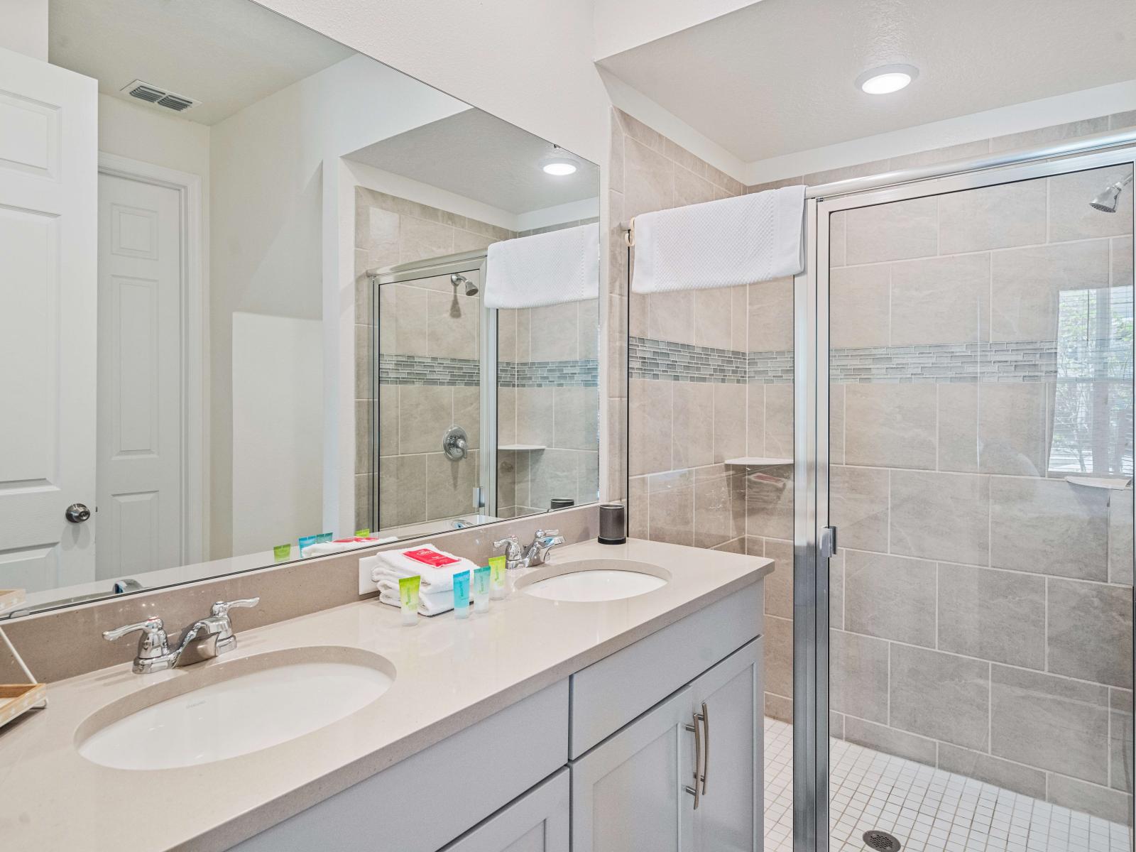 Polished Bathroom of the Townhouse in Kissimmee Florida  - Glass-enclosed walk-in shower area - Dual Vanity with large mirror - Sophisticated color palette creating a serene ambiance