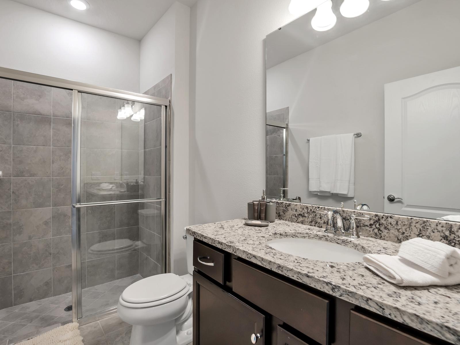 Classy bathroom of the townhouse in Davenport Florida - Glass-enclosed walk-in shower area - Neat and clean bathroom - Chic design featuring a sleek vanity and upscale lighting - Elegant lighting