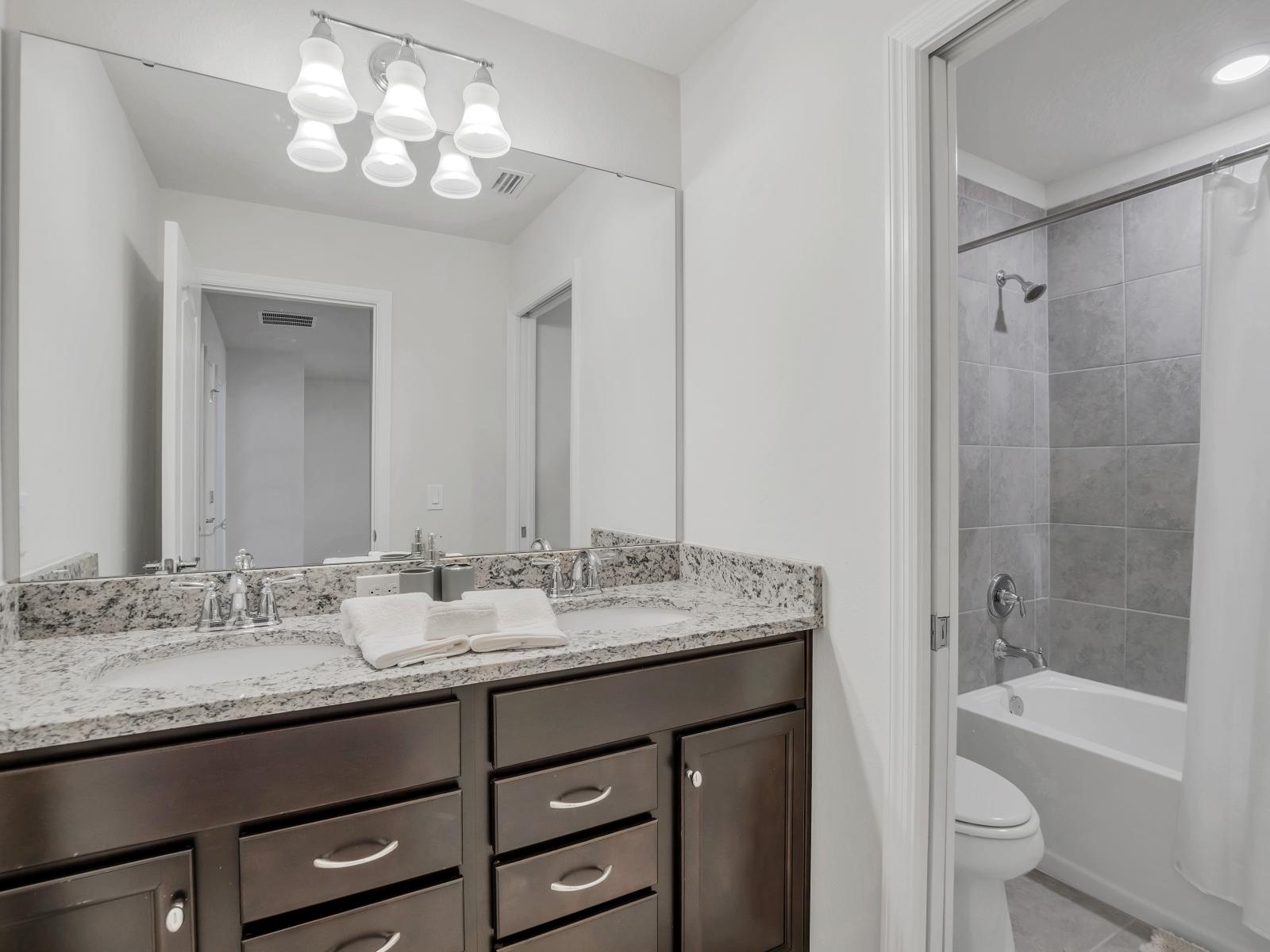 Polished bathroom of the townhouse in Davenport Florida - With bathtub and shower combo - Lush vanity with large mirror - Upscale lighting - Sliding curtain for added privacy