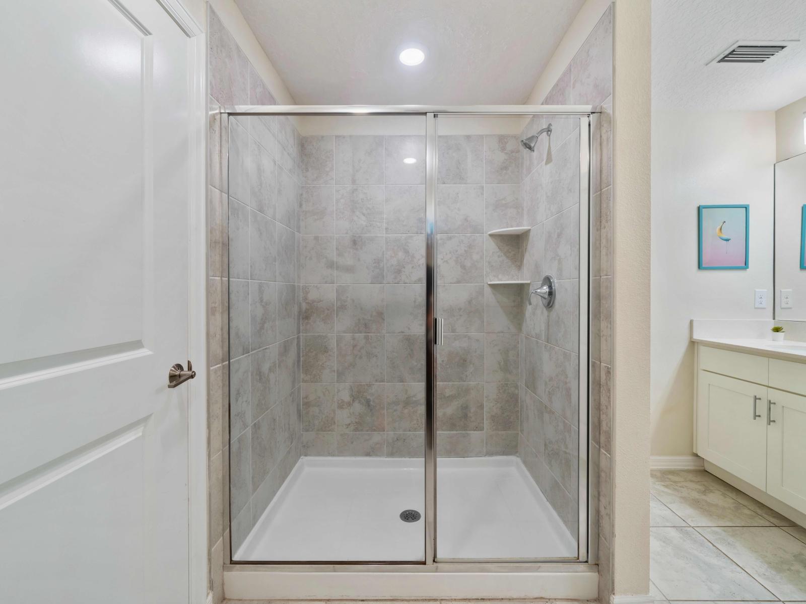 Polished Bathroom  of the Condo in Kissimmee Florida - Glass-enclosed walk-in shower - Sophisticated color palette creating a serene ambiance - Contemporary fixtures for a touch of indulgence