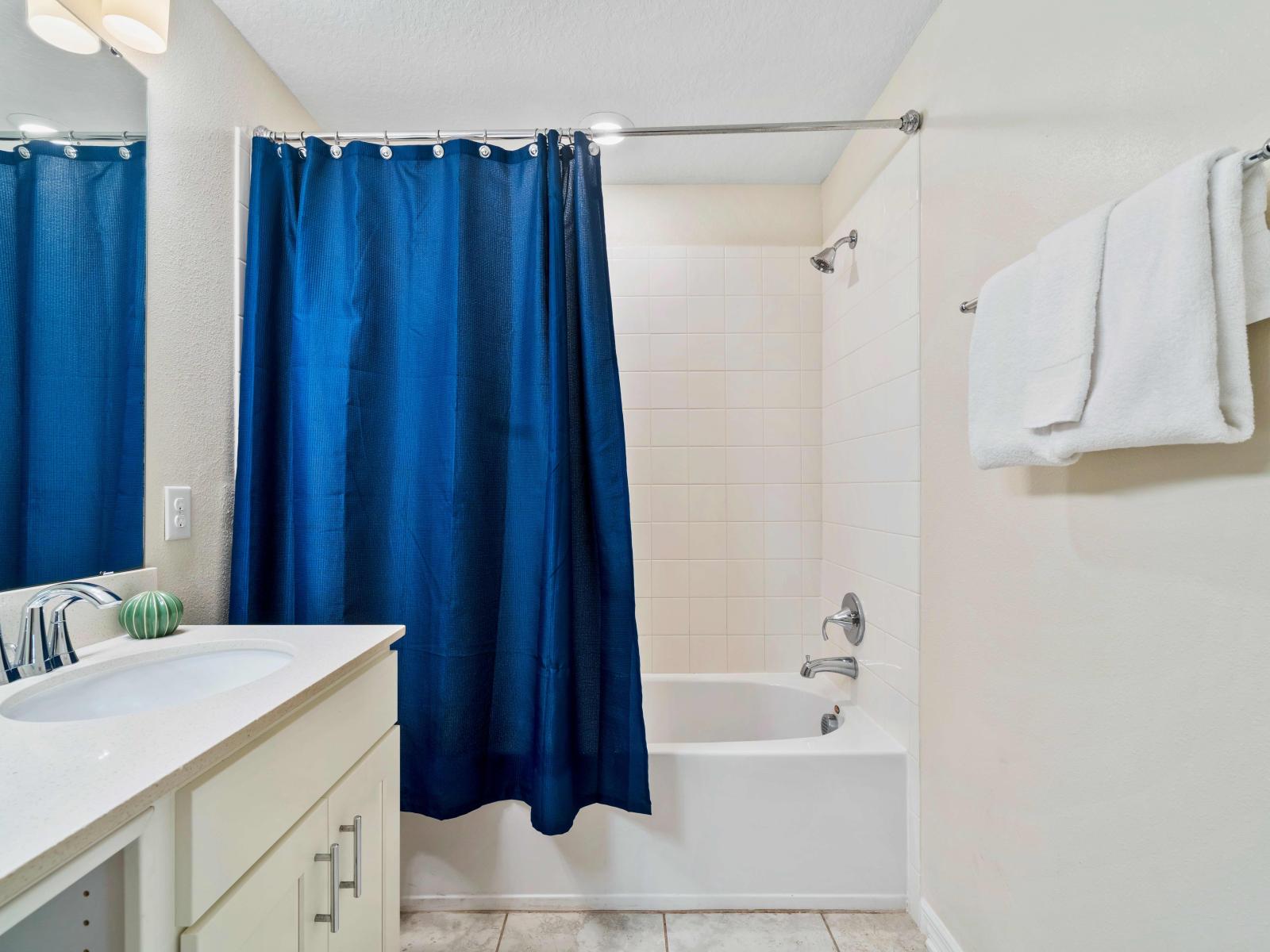 Regal Bathroom of the Condo in Kissimmee Florida - Bathtub with sliding curtains - Contemporary fixtures for a touch of indulgence - Understated elegance with clean lines and refined details