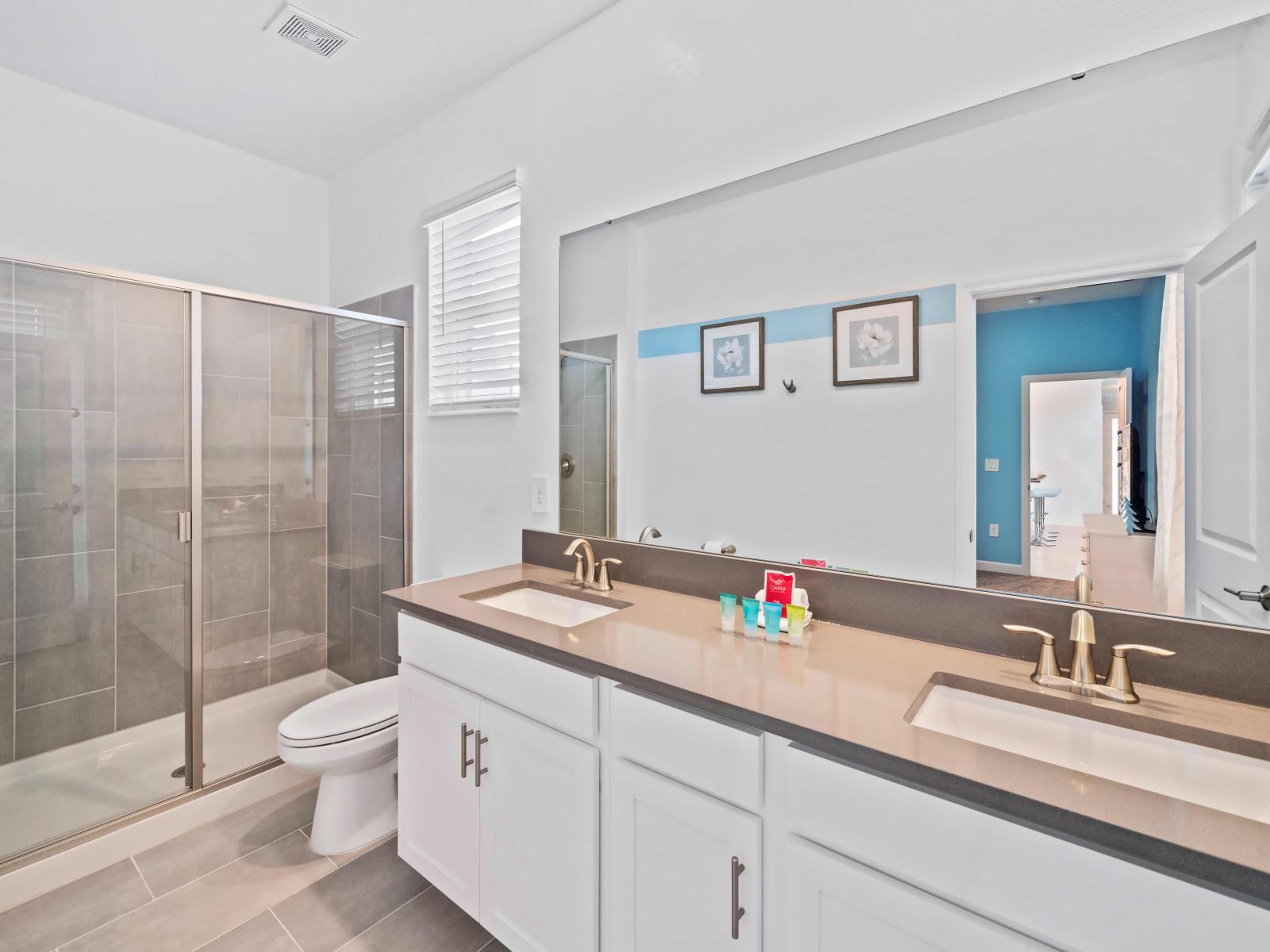 Opulent Tiled Bathroom of the Apartment in Kissimmee Florida - Glass-enclosed Shower Area  - Neat and Clean Toilet seat - Elegant lighting - Fantastic dual Vanity with large size wall mirror - Elegant storage space