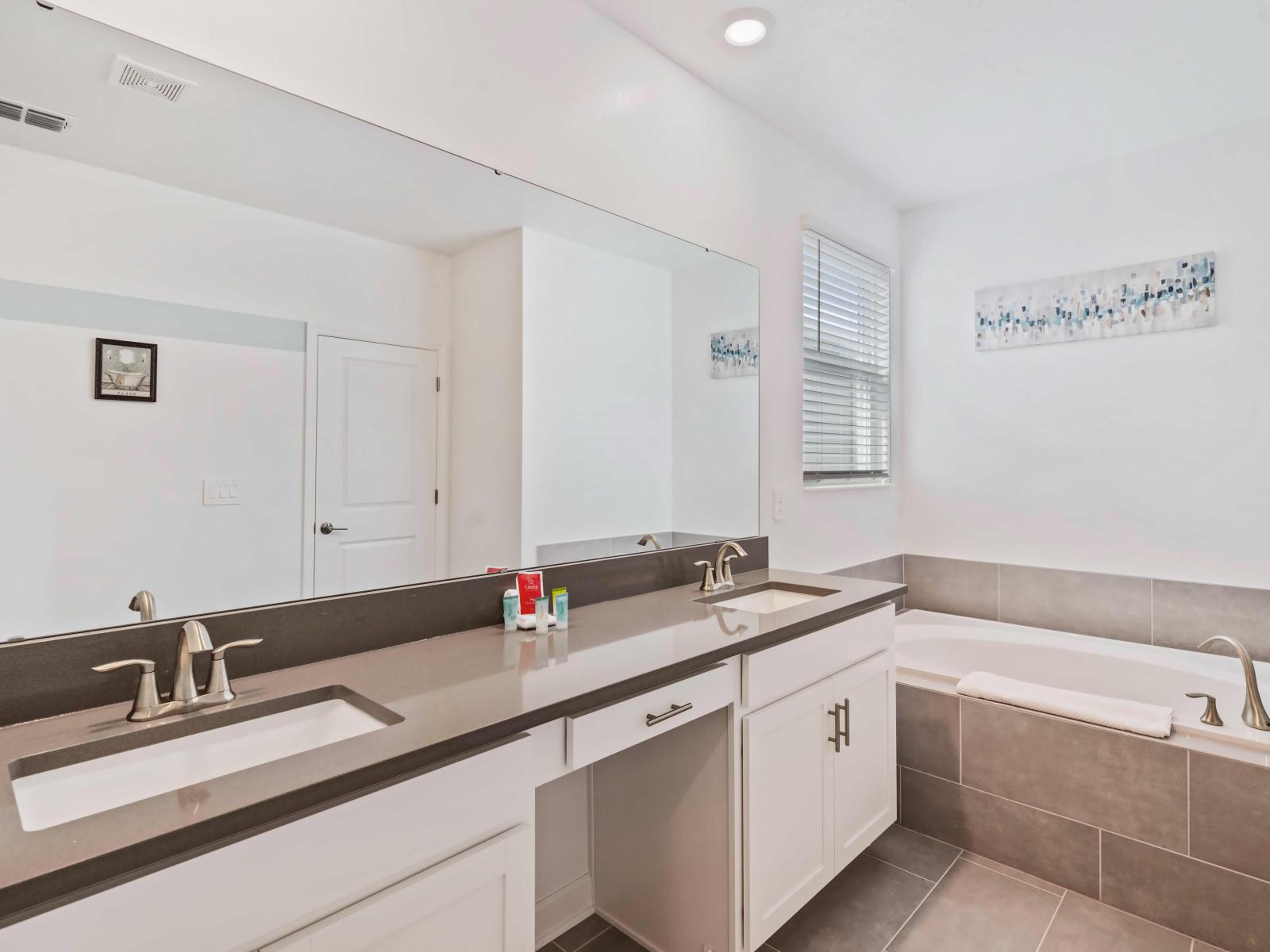 Enjoy privacy and comfort in this beautifully designed bathroom of the home in Kissimmee - Soft lighting provide a cozy atmosphere. - Take in stunning vistas from the window while soaking in the tub. - Twin sink vanity with plenty storage space