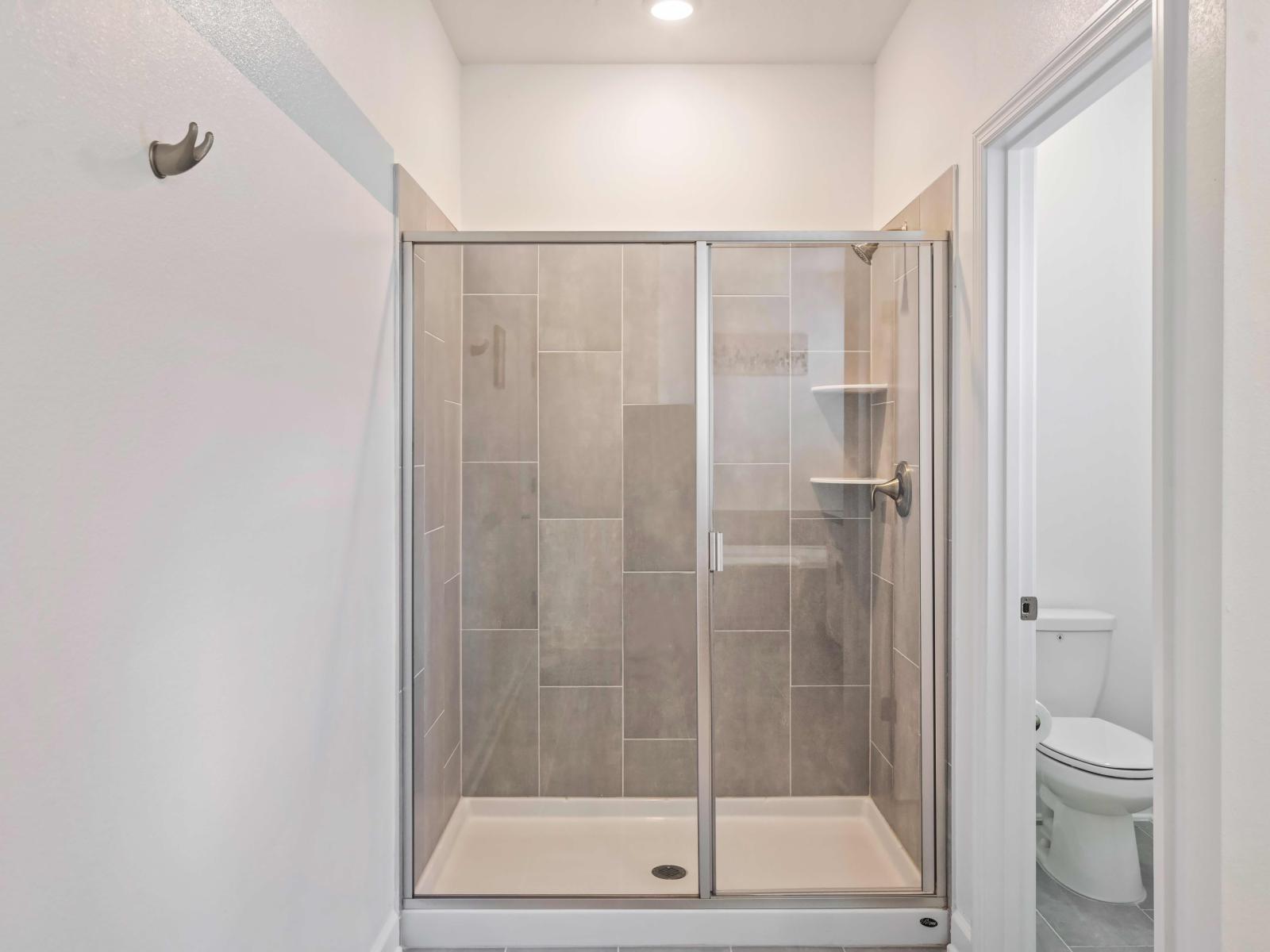 Experience the epitome of relaxation in our spacious walk-in shower area in the bathroom of the home in Kissimmee - Immerse yourself in modern elegance with our beautifully appointed walk-in shower area - Cozy entrance through glass sliding doors