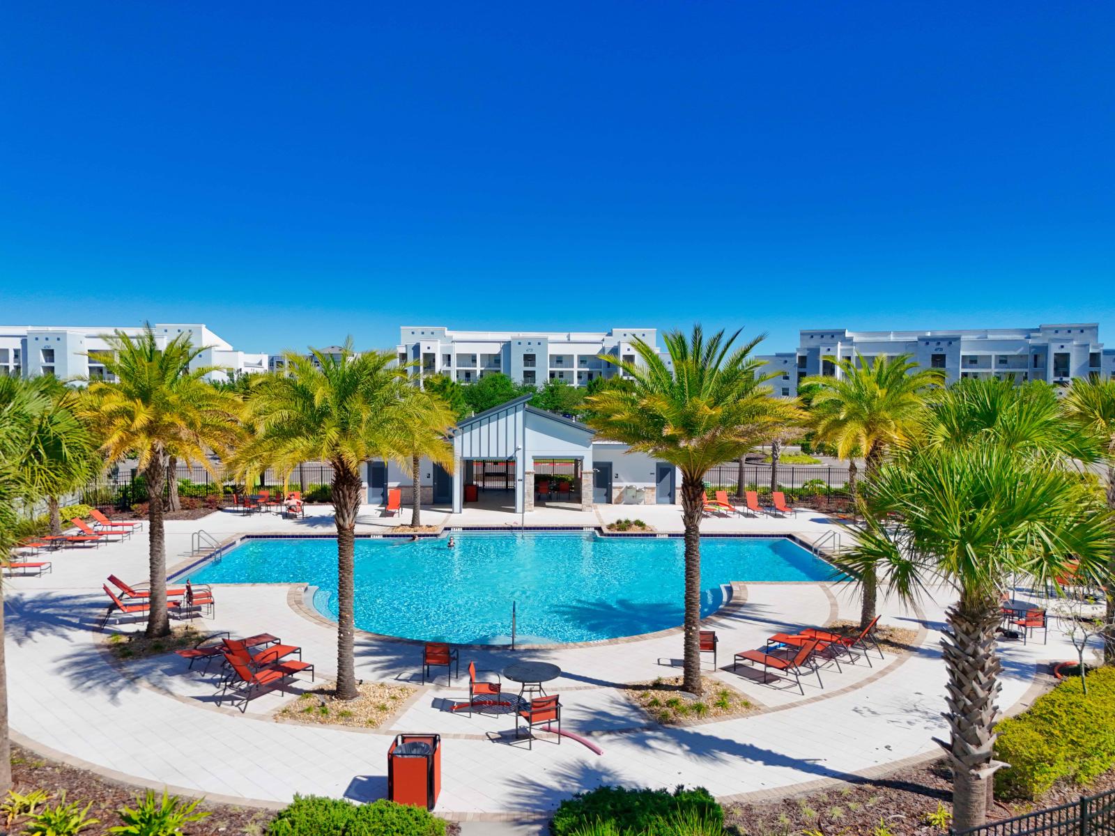 Spectacular Pool area of the resort in Kissimmee - Space covered with refreshing plant and trees - Lush Environment - Cozy Beach Chairs available to relax on the poolside in completely sunbathed space - Stunningly designed Big Pool with Fresh water