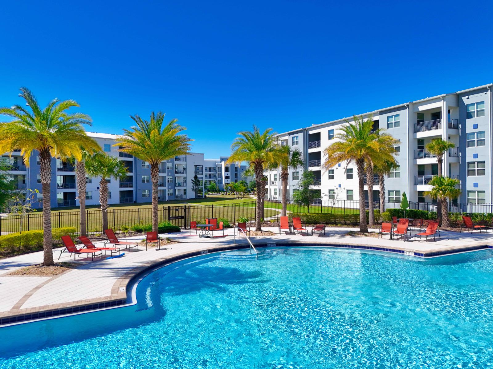 Enjoy the Freshness during your stay in our Pool in Kissimmee - Refreshing space surrounded by plants and trees - Cozy beach chairs available for having sunbath