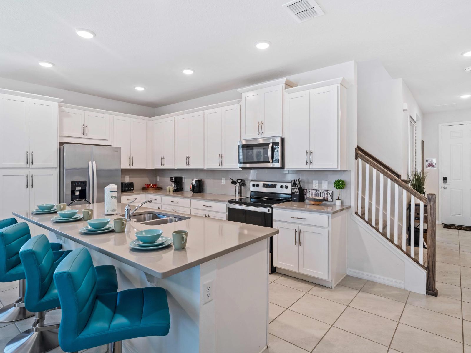 Exquisite and fully-equipped kitchen in the Kissimmee home - Plenty storage space and user-friendly layout for seamless cooking experiences - Comprehensive assortment of kitchen -essentials - High-quality breakfast bar with chairs for added comfort