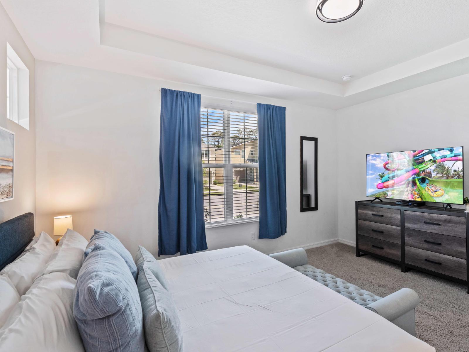 Lavish bedroom in the Kissimmee home - Featuring a plush bed with impeccably clean linens - Large windows offering breathtaking outdoor views - Elegantly carpeted floor for added comfort - Charming bedside table lamps and tasteful wall art.