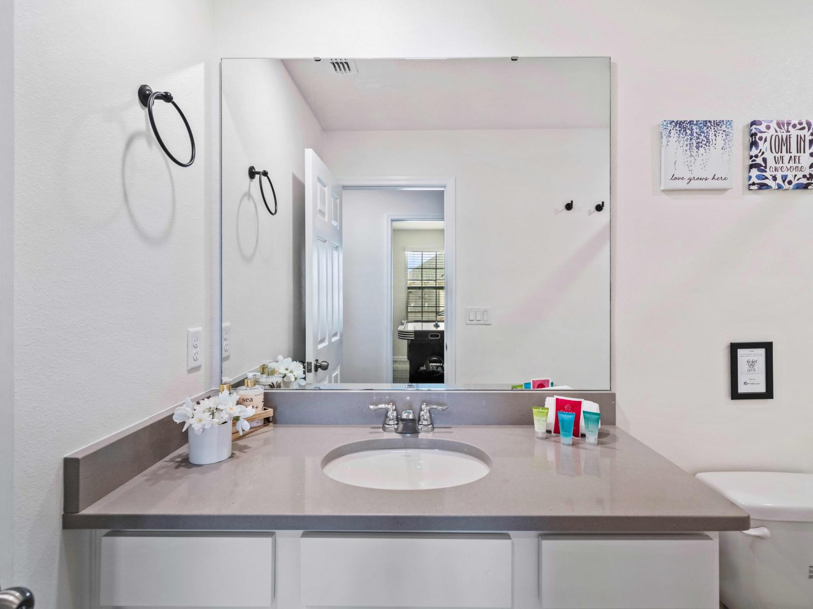 The Kissimmee home showcases a luxurious bathroom - Highlighting a spacious vanity area - The toilet seat is impeccably clean ensuring both hygiene and comfort - Visually appealing glass enclosed shower space - Bathroom is adorned with elegant tile