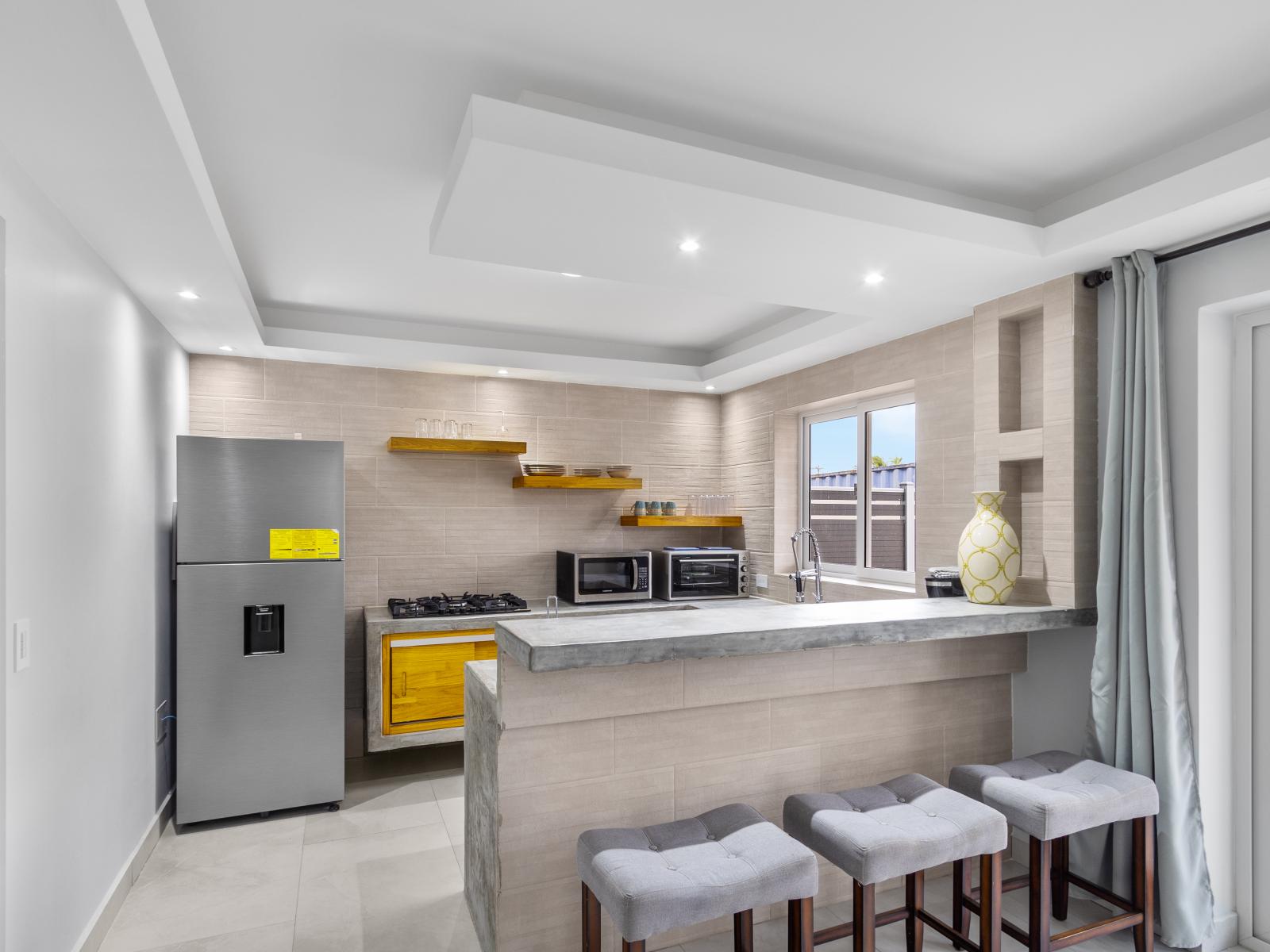 Modern kitchen of the apartment in Oranjestad Aruba - Breakfast bar and high chairs - Functional layout designed for efficient meal preparation - Thoughtful placement of kitchen essentials for easy access