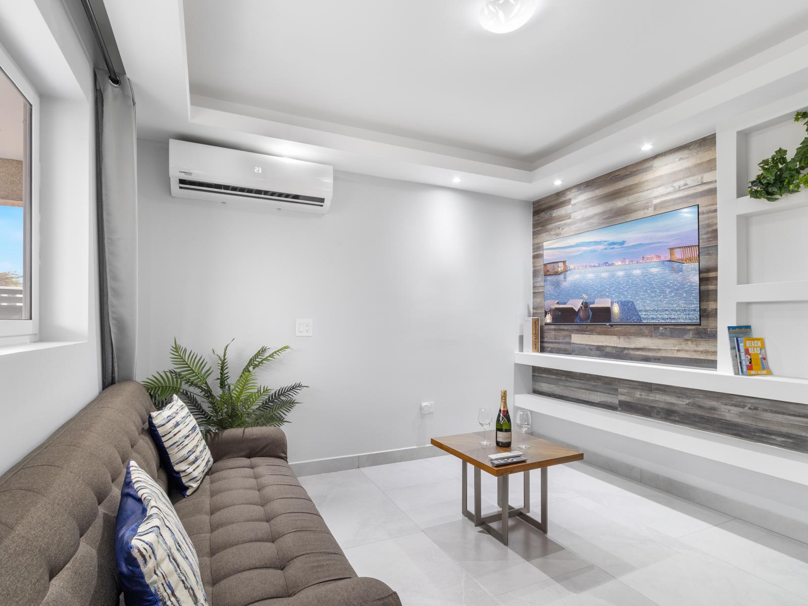 Bright living area of the apartment in Oranjestad Aruba - Comfort meets style with wall mounted flat screen smart TV - Elegantly decorated space with a neutral color palette for a timeless appeal - Plush sofa for ultimate relaxation