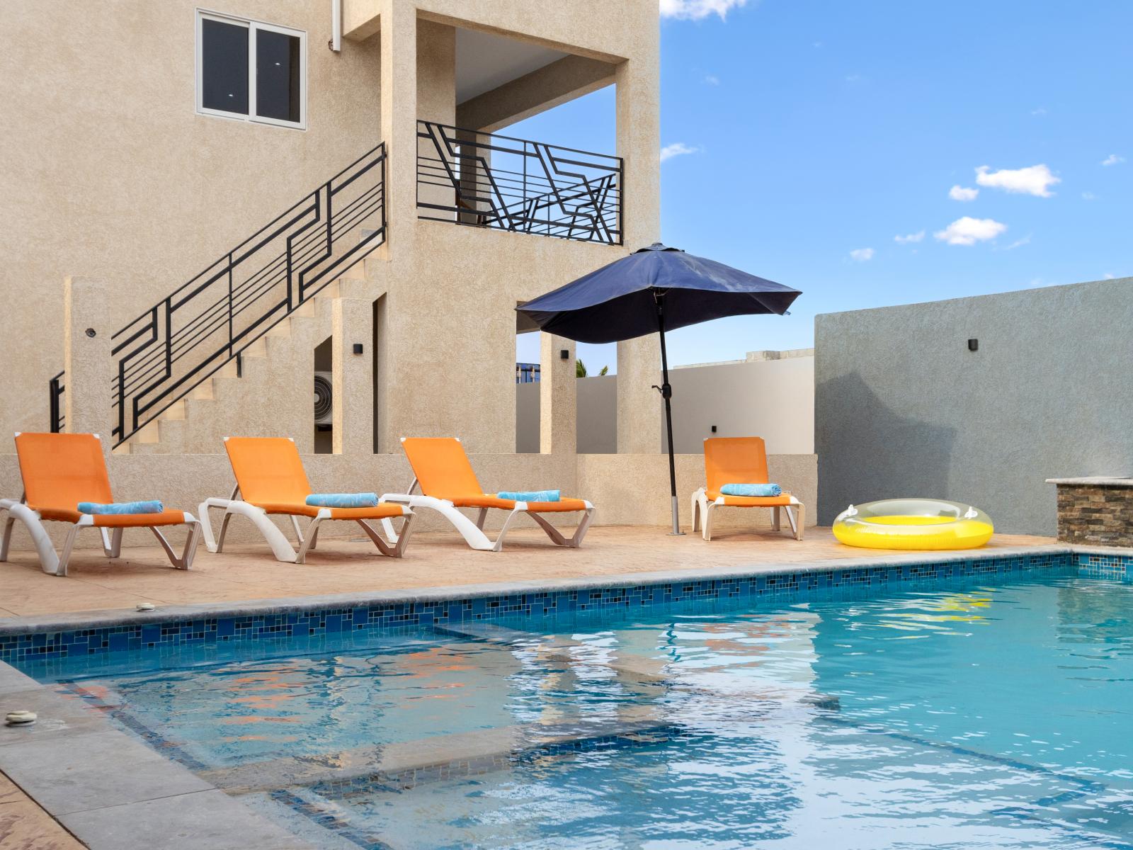 Beautiful shared pool area of the apartment in Oranjestad Aruba - Umbrella by the pool for sensitive guests - Inviting waters perfect for a leisurely swim or refreshing dip - Comfortable loungers for lounging and soaking up the sun