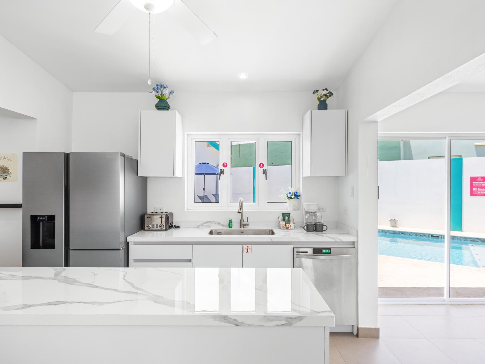 - Bright, modern kitchen with sleek countertops and stainless steel appliances - Convenient island with plenty of space for meal prep and casual dining - Easy access to the pool area through adjacent sliding glass doors, perfect for outdoor dining