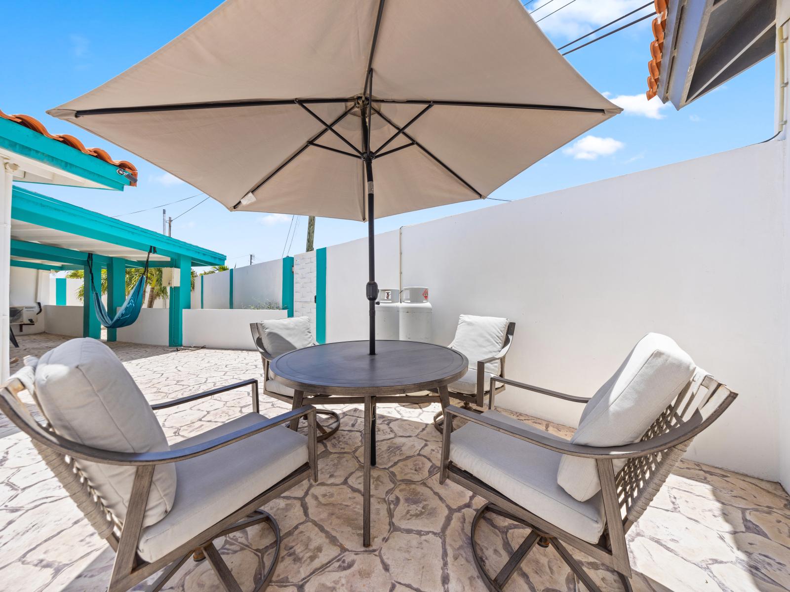 - Comfortable outdoor seating under a large umbrella, perfect for relaxing in the shade - Ideal spot for enjoying morning coffee or evening drinks while escaping the midday sun - Convenient access to nearby amenities, including the pool and BBQ area