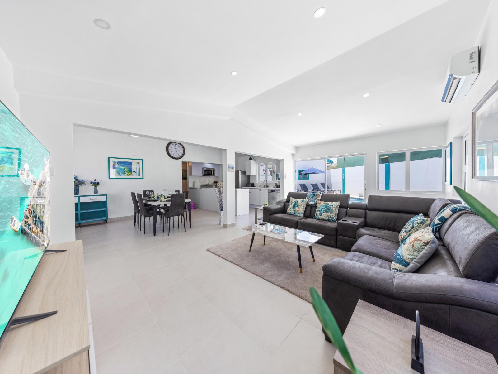 - Bright and spacious living area with natural light from numerous windows - Modern furnishings create a welcoming and comfortable environment for relaxation - Seamless flow between the kitchen, dining, and living areas creates a lively atmosphere