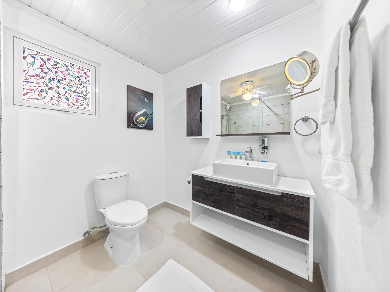 - Bright and airy bathroom with modern fixtures and a spacious vanity - Enjoy the contemporary design, perfect for a refreshing start to your day - Thoughtful details like a magnifying mirror and stained glass window elevate the experience