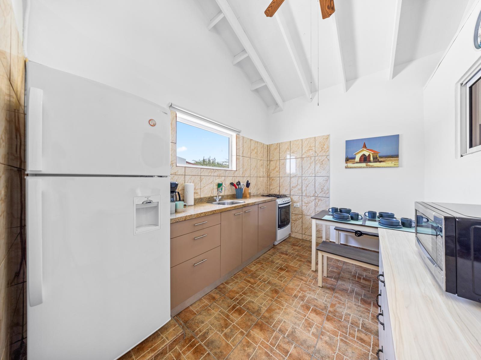 - A fully equipped kitchen with a dining area perfect for family meals - The high ceilings and large window bring in natural light, enhancing the kitchen's welcoming atmosphere - The clean, functional design makes this kitchen a joy to cook in