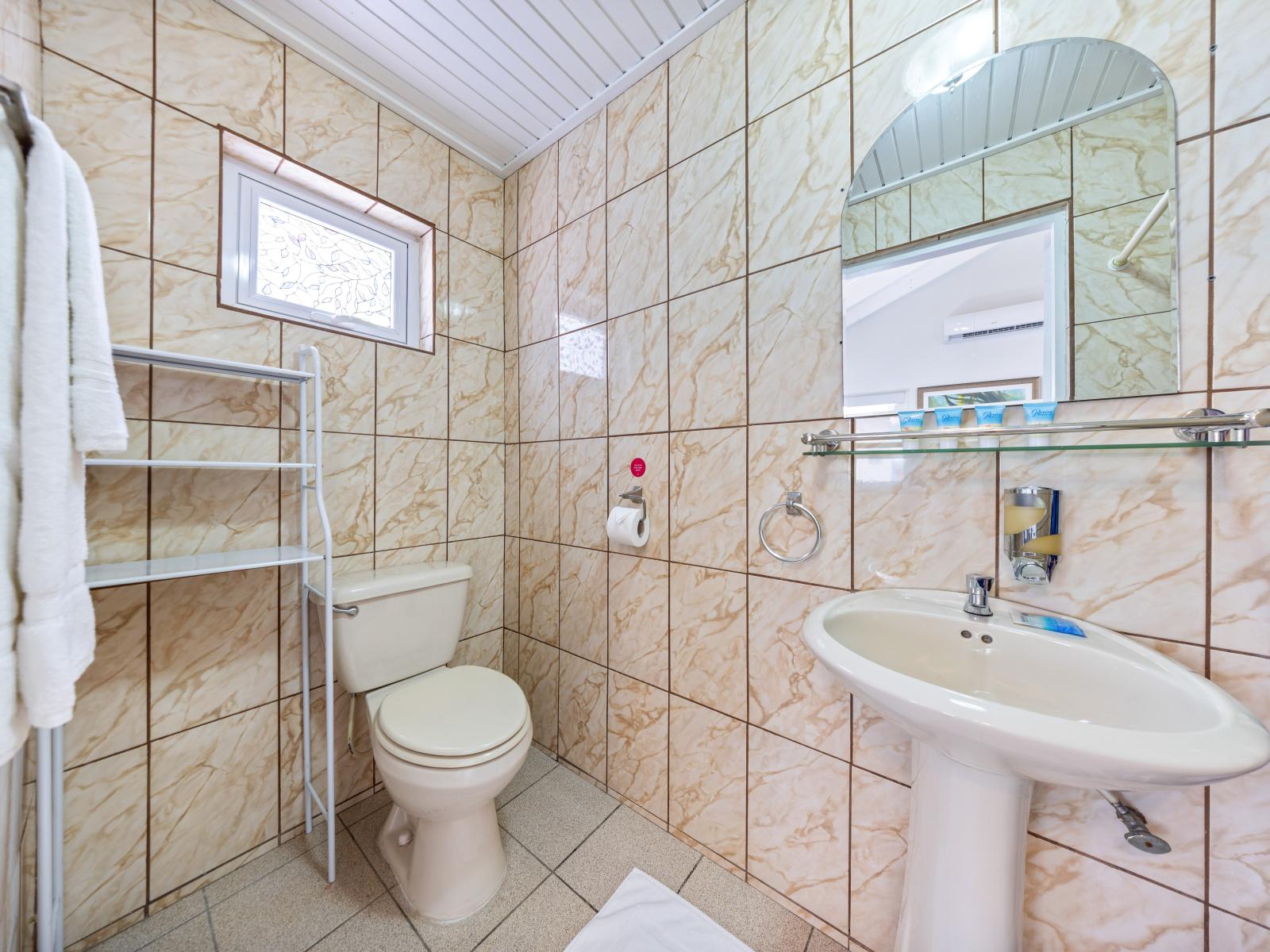 - Bright and clean bathroom featuring elegant tile work and modern fixtures - Compact layout ensures convenience with all essentials within easy reach for a peaceful stay - Large mirror and plenty of lighting make this space perfect for getting ready