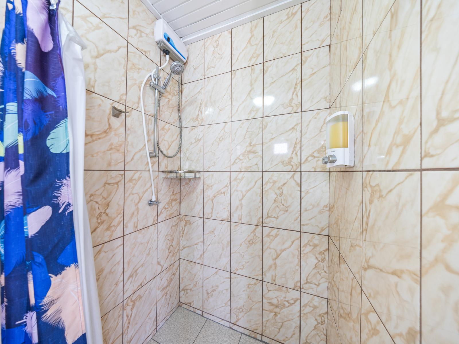 - Refreshing walk-in shower with sleek, marbled tiles creating a serene atmosphere - Equipped with modern fixtures and a handy shower caddy for your essentials - Vibrant curtain adds a splash of color, enhancing the bathroom's overall appeal