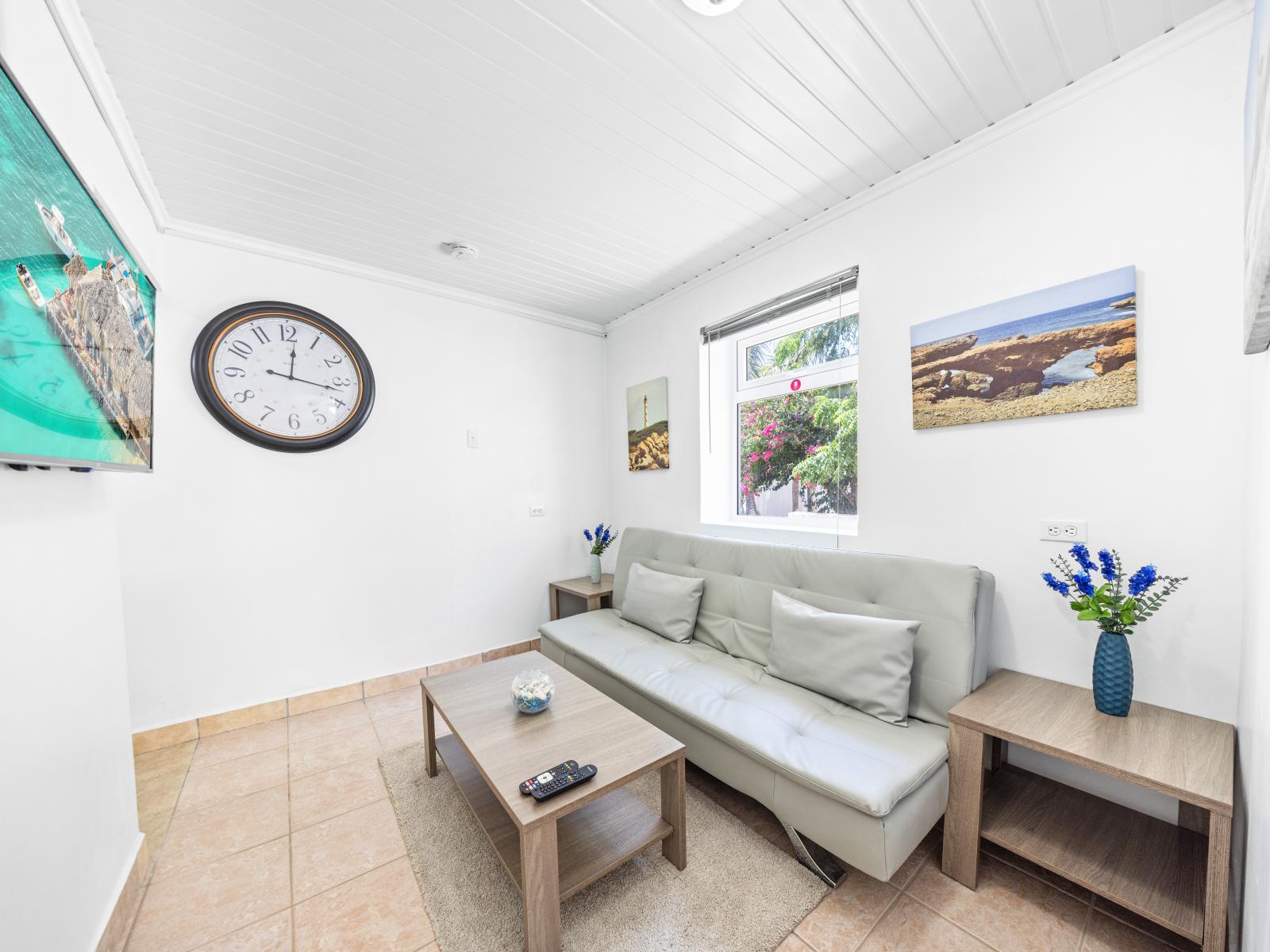 - Cozy sitting area with a plush sofa, ideal for relaxing after a day of adventure - Large windows allow natural light to flood in, offering views of the vibrant greenery outside - Wall-mounted TV surrounded by tasteful decor for your entertainment