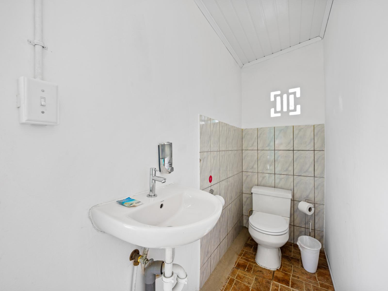 - Convenient half bathroom for quick freshening up, located just steps away from the pool area - Simple yet functional design with essential amenities for comfort and ease - Ideal for guests, ensuring everyone has easy access without going indoors