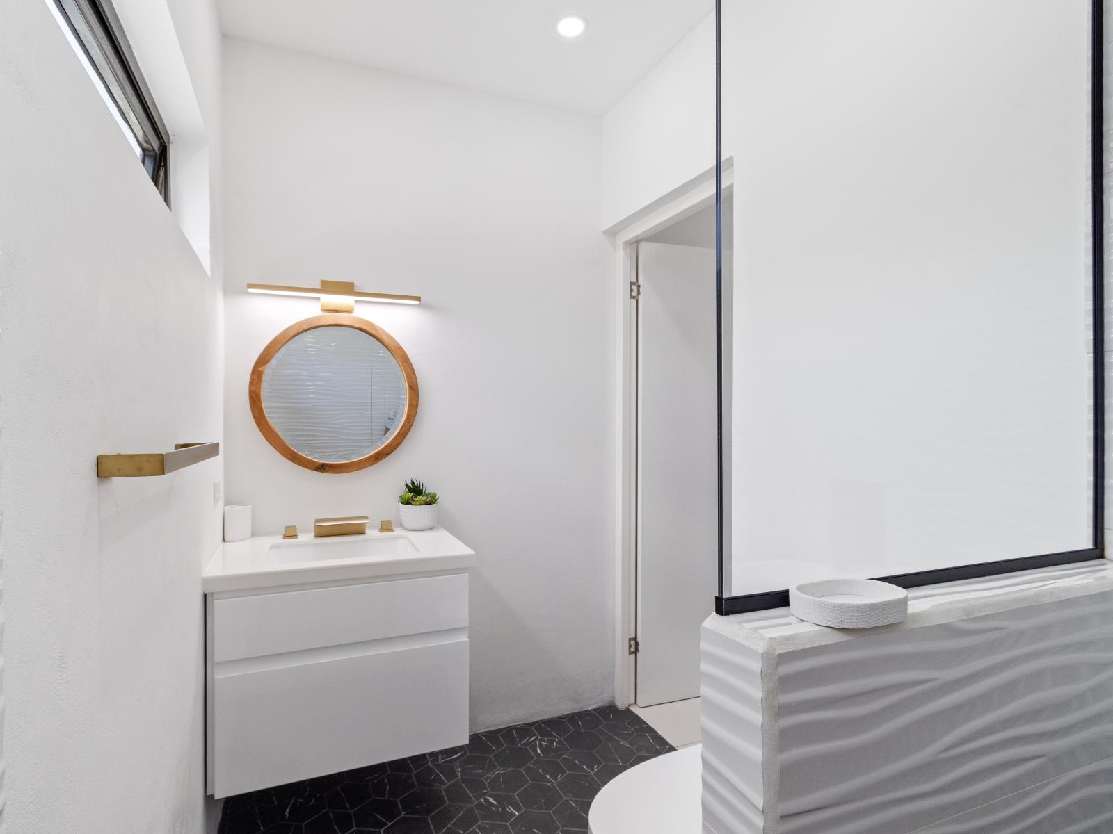 Lavish bathroom of the home in Oranjestad Aruba - Chic vanity with upscale lighting and stylish round shape mirror - Walk-in shower area