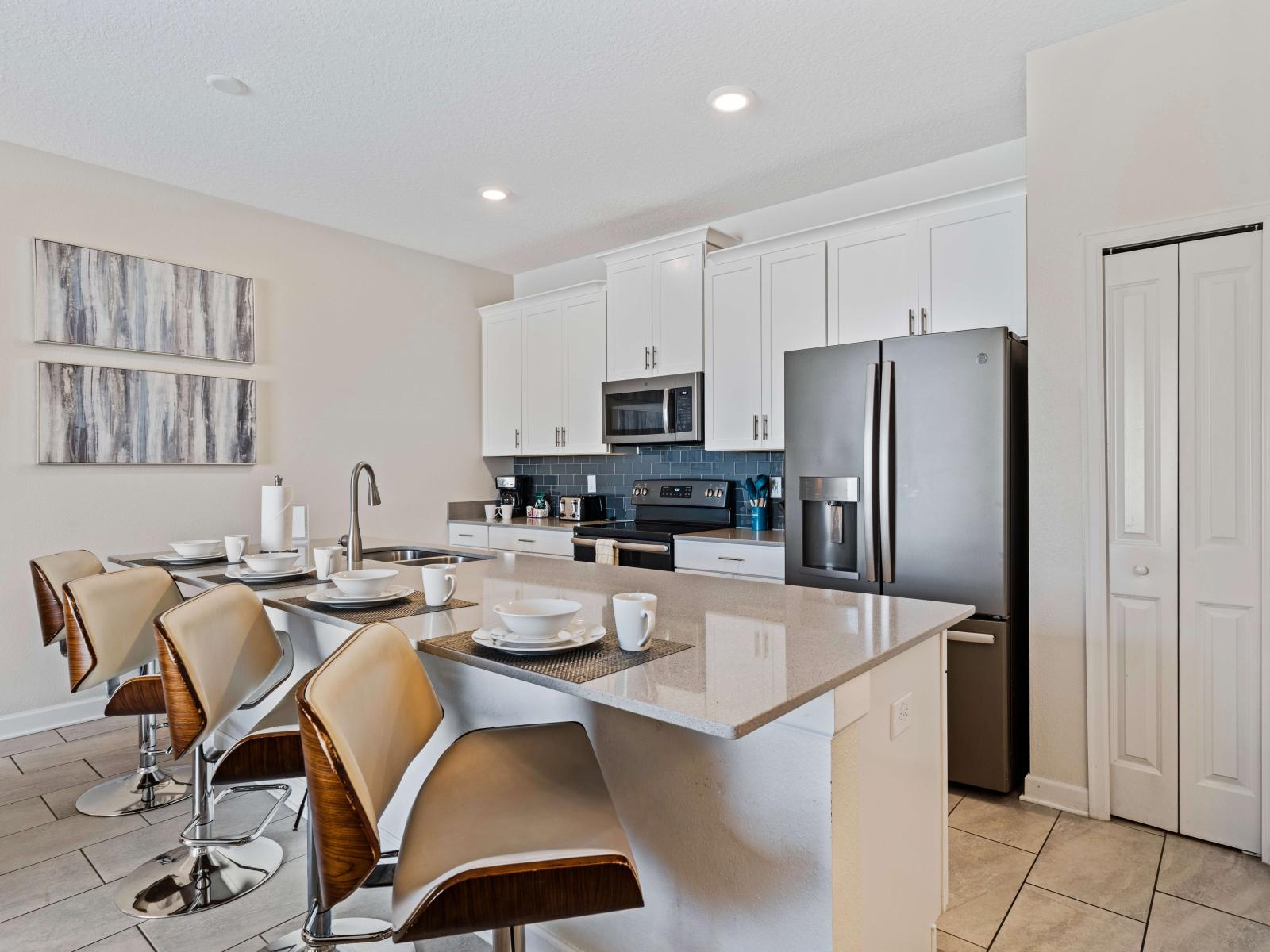 Full equipped kitchen of the townhouse in Kissimmee Florida - Breakfast bar and high chairs - Integrated appliances for a seamless and stylish appearance - Contemporary design with clean lines and minimalist aesthetics