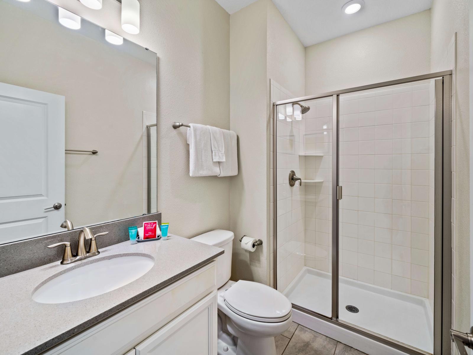 Swish bathroom of the townhouse in Kissimmee Florida - Vanity with upscale lighting and large mirror - Spacious shower stall with sliding glass door