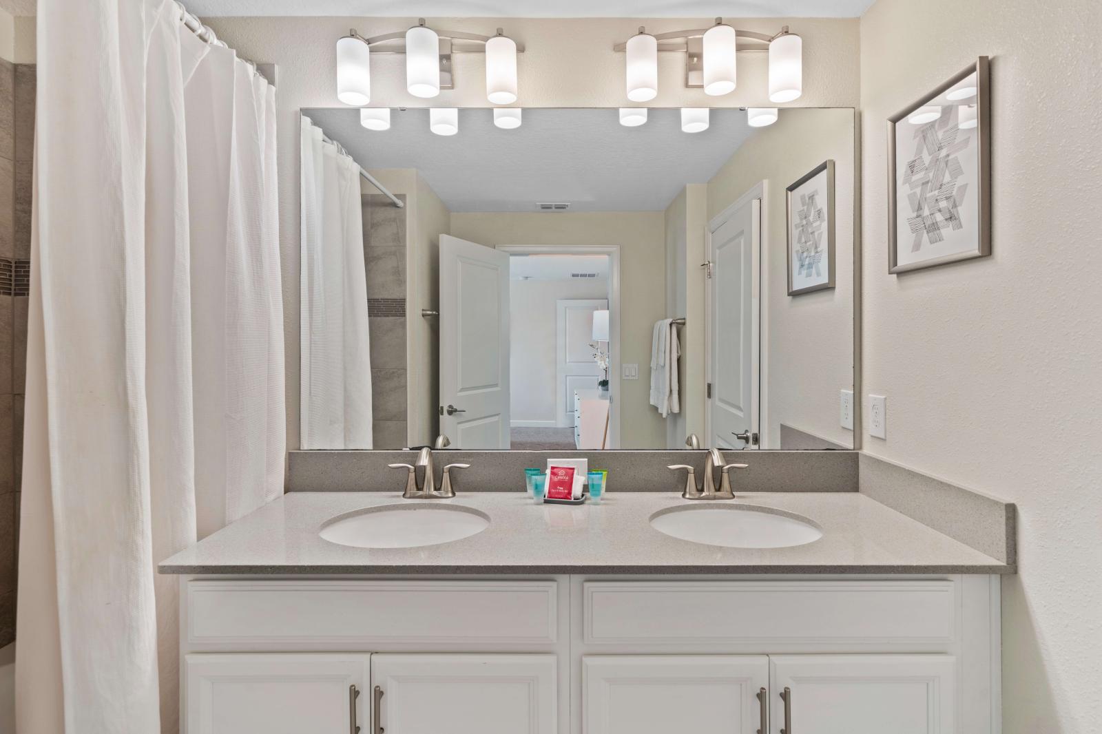 Polished bathroom of the townhouse in Kissimmee Florida - Bathtub and a shower combo - Chic design featuring a sleek dual vanity and upscale lighting