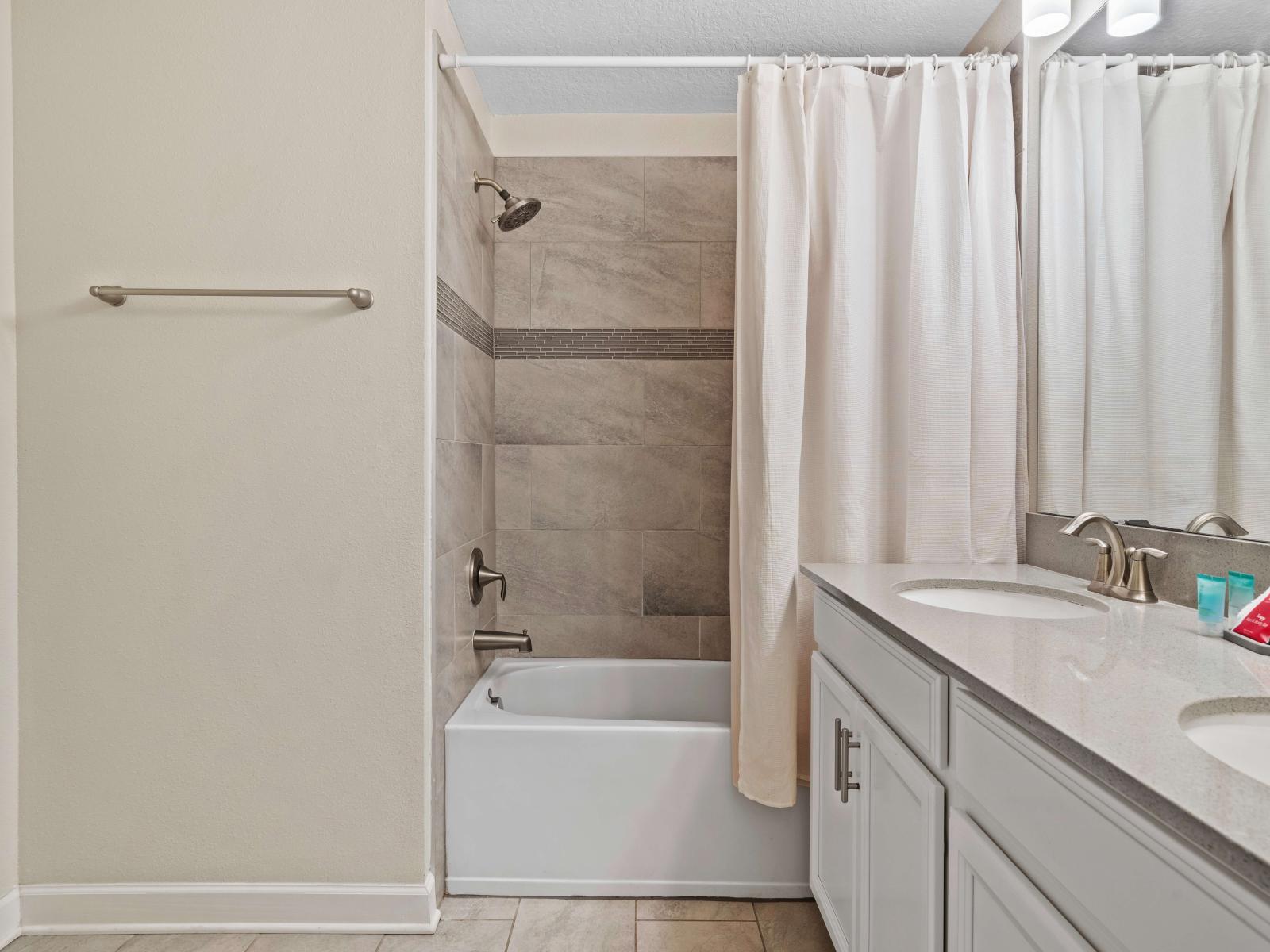 Tranquil bathroom of the townhouse in Kissimmee Florida - Bathtub and a shower combo with sliding curtains for added privacy - Sophisticated color palette creating a serene ambiance - Understated elegance with clean lines and refined details