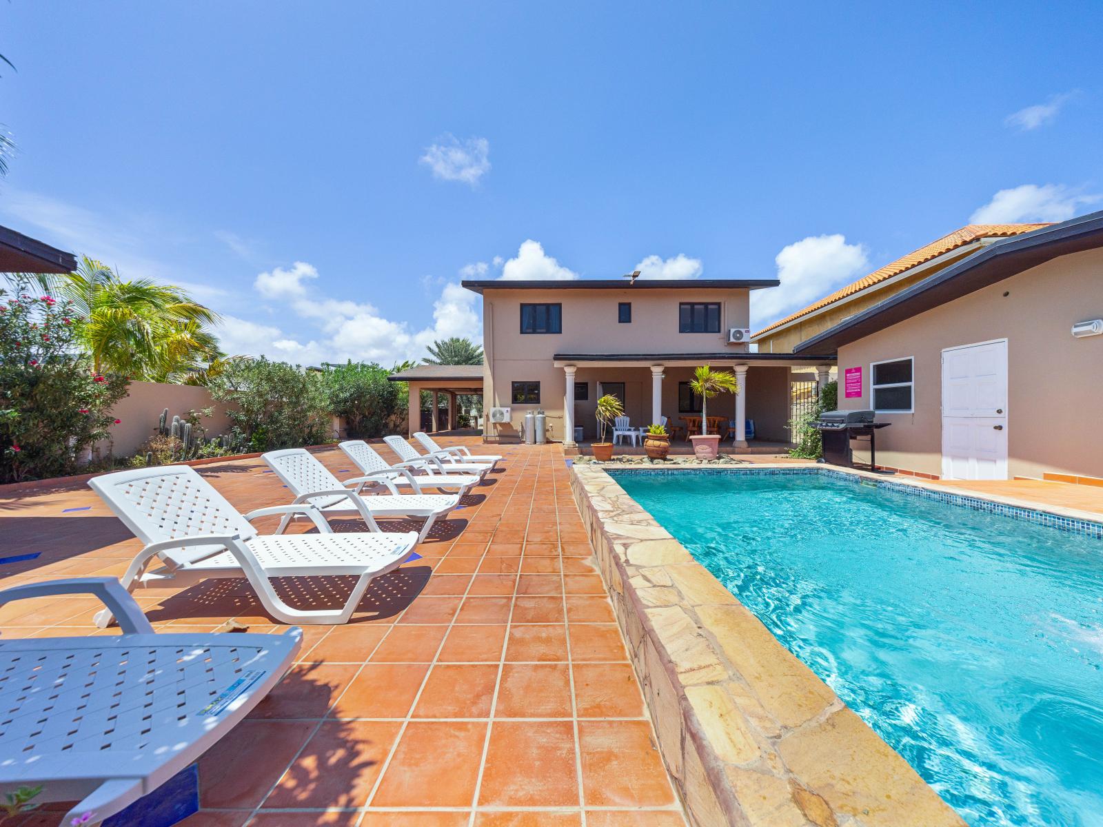 Escape to aquatic adventures in spacious and inviting pool area of the home in Noord Aruba - A serene ambiance where worries melt away and memories are made - A picturesque setting surrounded by tropical blooms and swaying palms