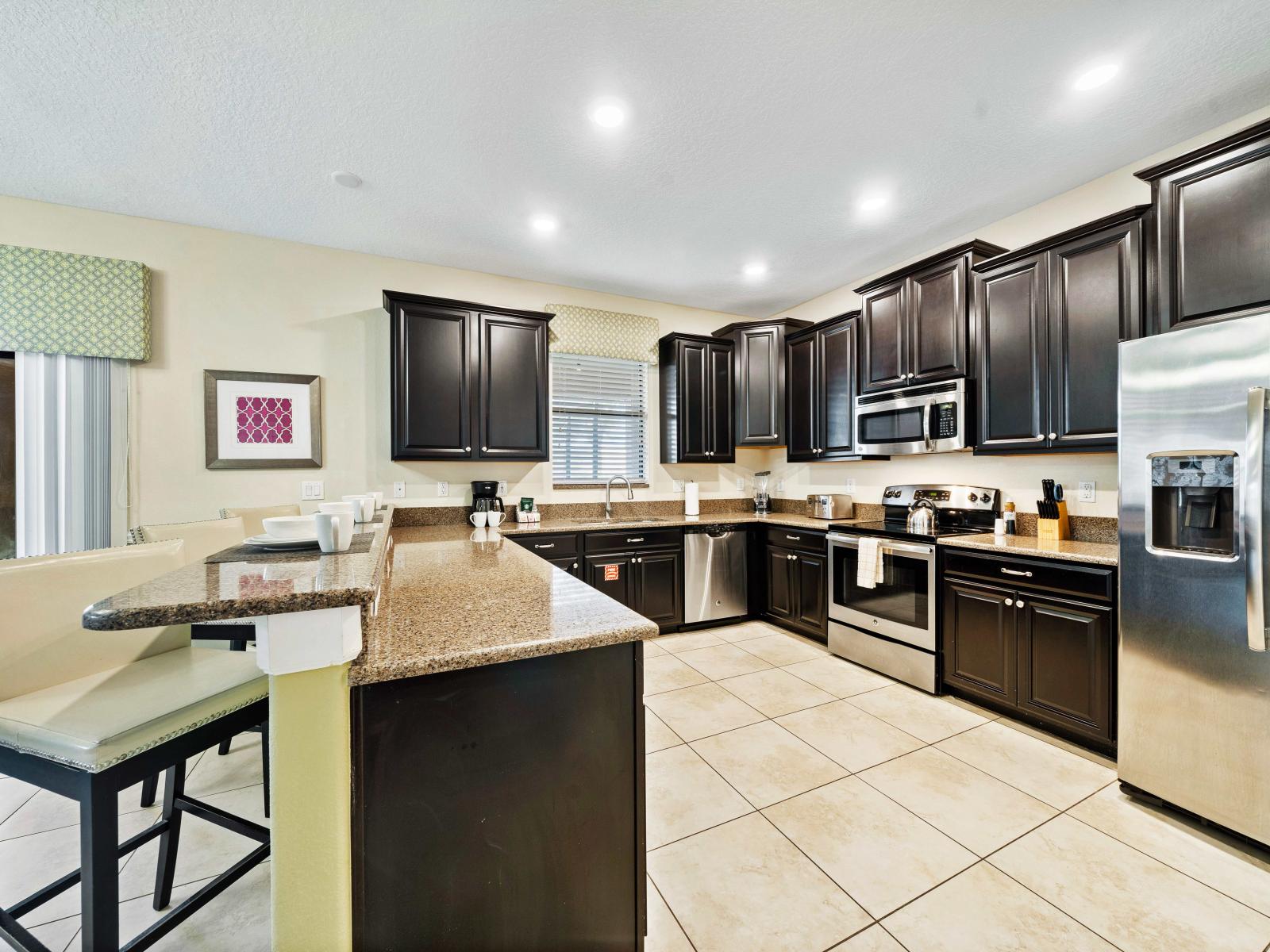 Modern kitchen with quality appliances and sleek countertops, perfect for cooking enthusiasts - plenty of cabinet space, a breakfast bar with high chairs and island make meal prep a breeze - Contemporary finishes, ensuring a delightful experience