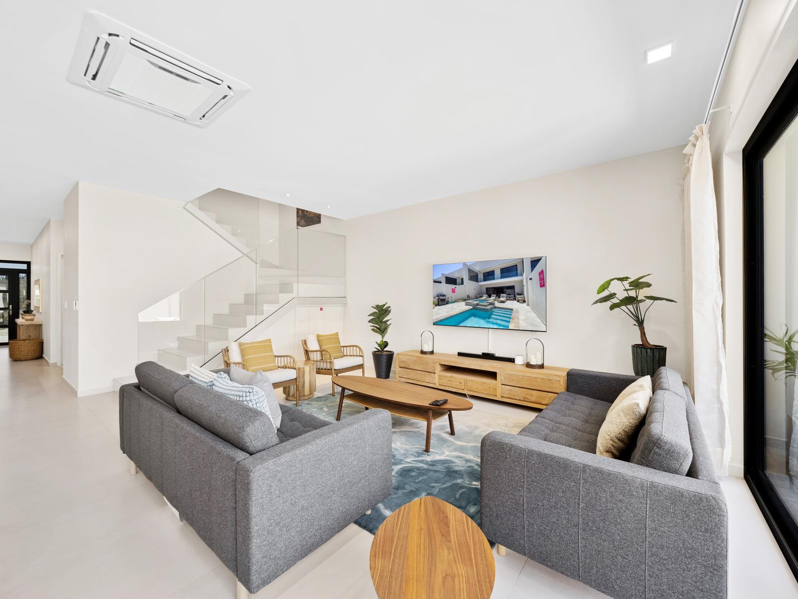 Experience the epitome of comfort in spacious living area of the apartment in Noord Aruba - Featuring plenty of seating, smart TV and serene ambiance invite you to unwind - Easy access to backyard with pool, dining and lounge for outdoor moments